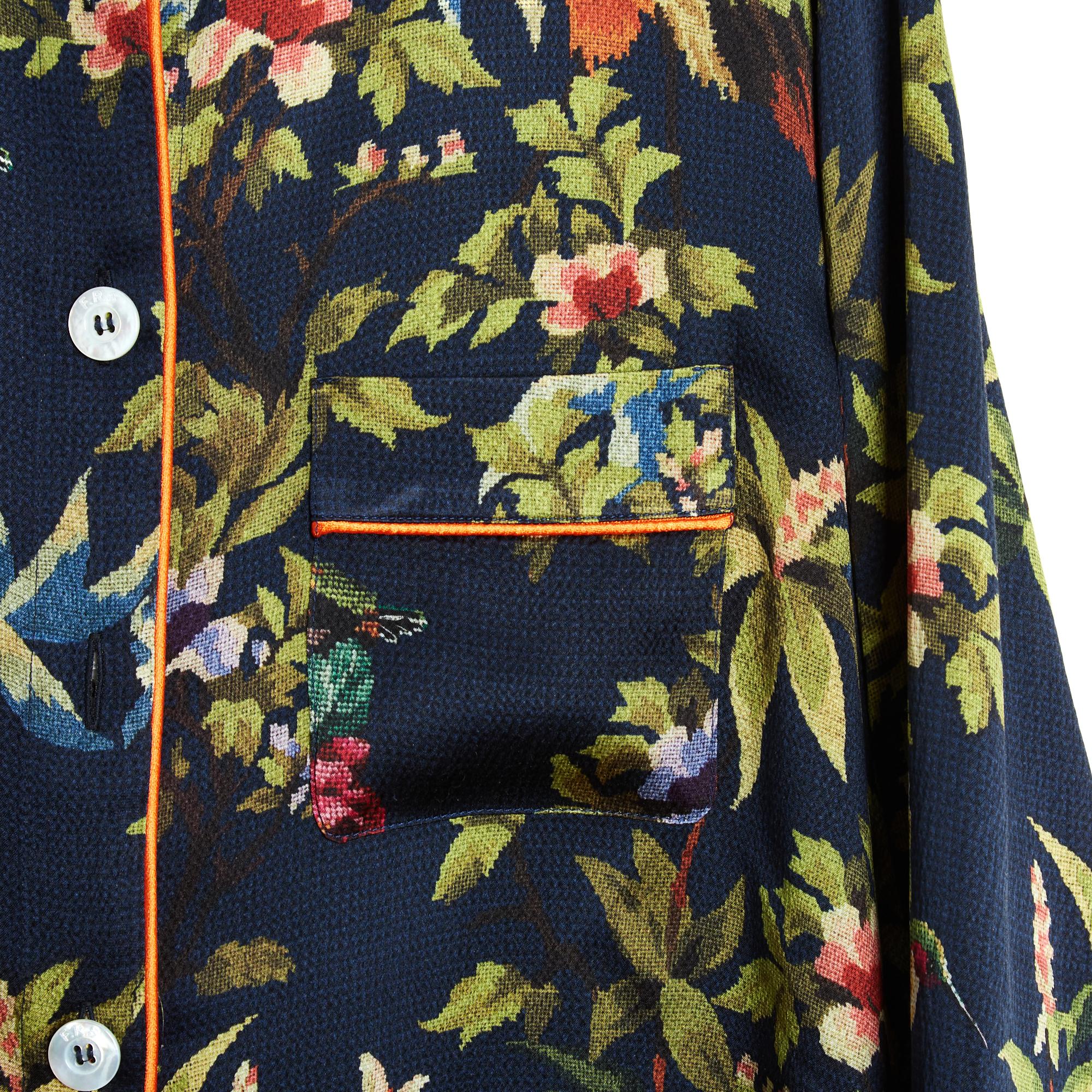 Top F.R.S. For Restless Sleepers, blusa oversize ispirata al pigiama in crêpe di seta blu navy stampata con un motivo esotico a punto croce (stile arazzo) nei toni del verde e del rosa, bordata con profili rosso corallo intorno al colletto, al