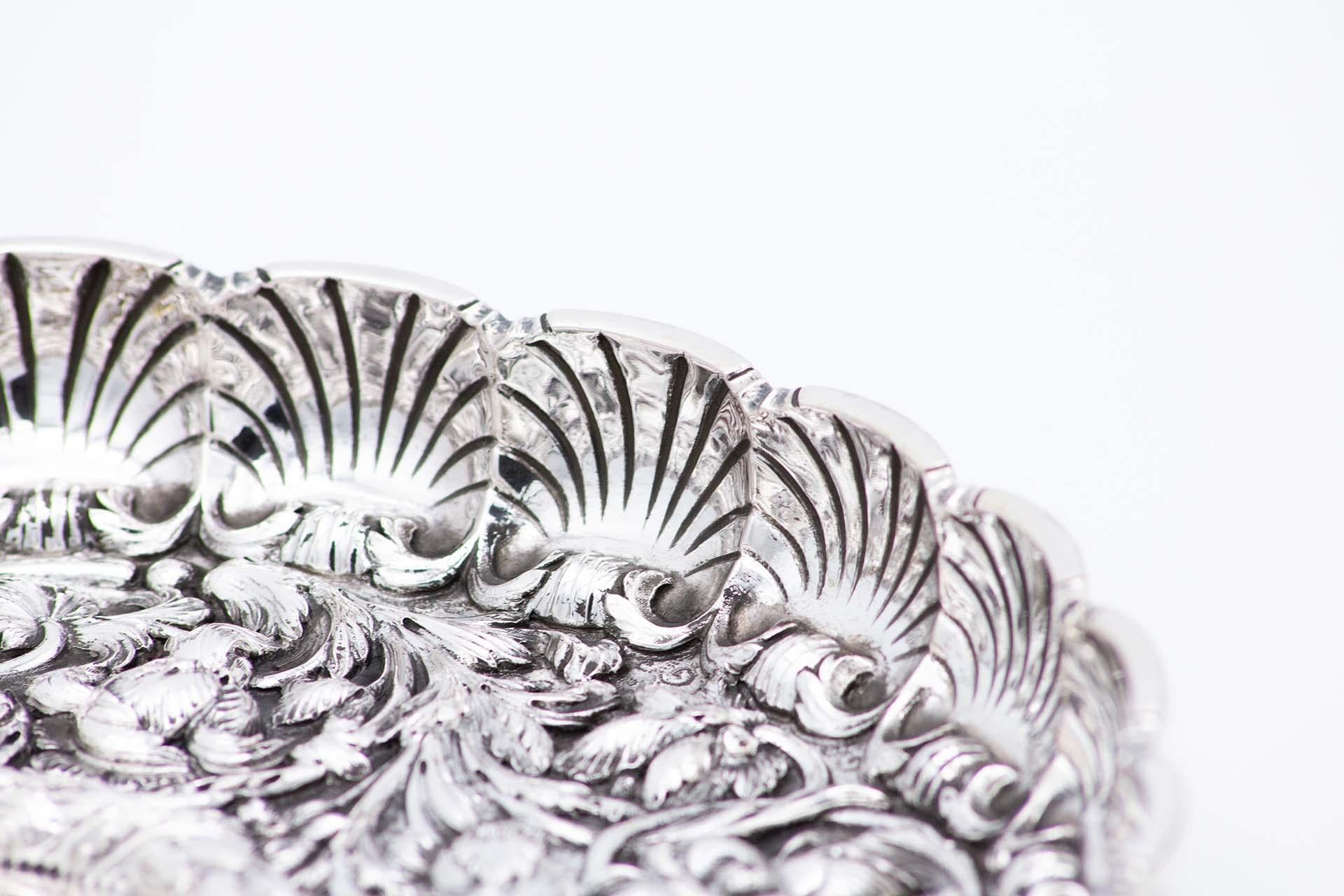 Description: Fruit bowl centerpiece in silver profusely embossed with acanthus flowers and leaves, shells and lobed rim. Metal: Silver. Origin: Portuguese. Brand: javali II Title. Weight: 711.04 grams. Dimensions: 28.6cmx3.4cm. Content: 833/1000.