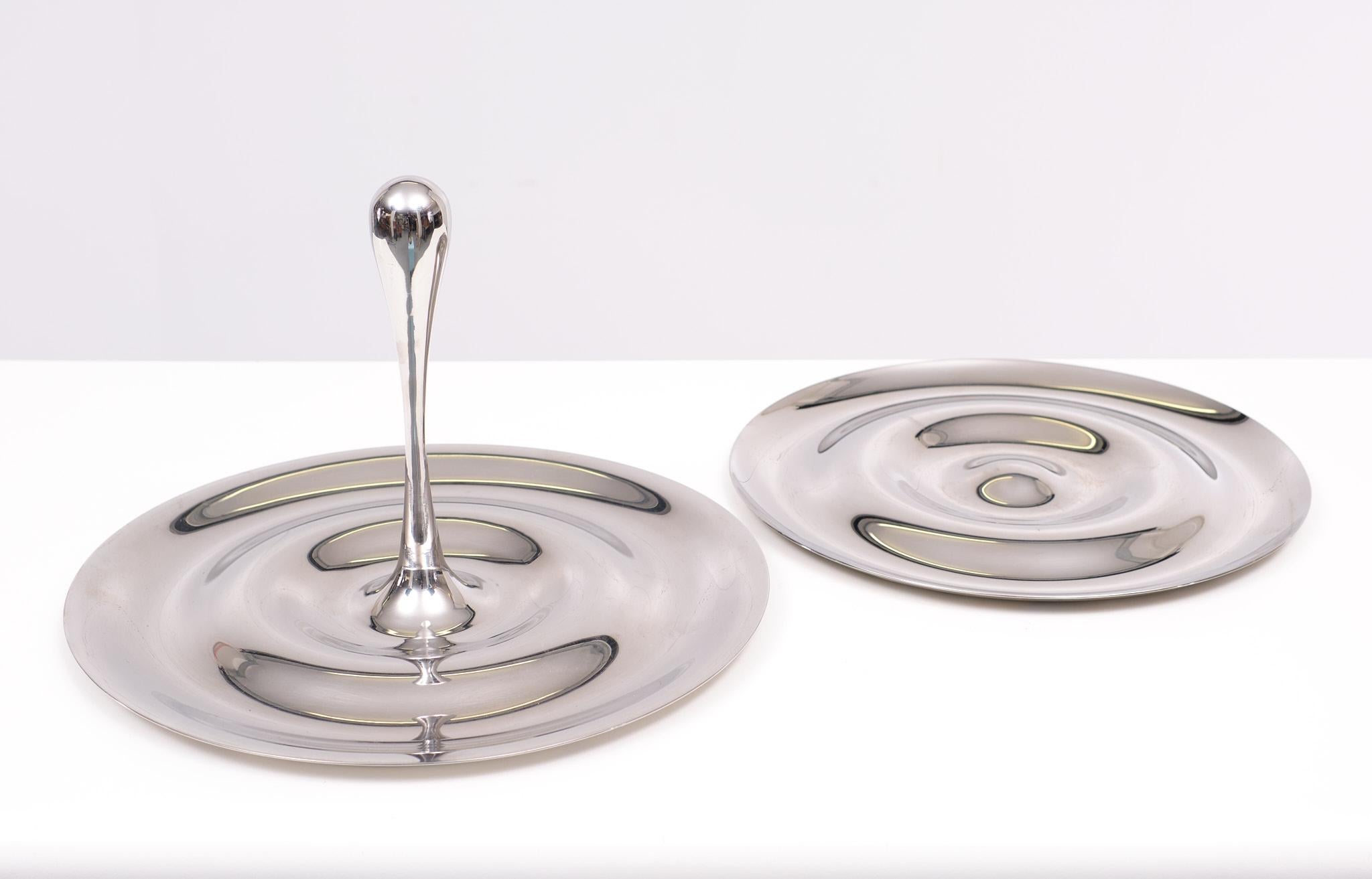 The design inspired by nature: a drip falling into the water where it causes ripples.
Manufacturer: RoyalVKB ( Royal van Kempen & Begeer ) period 2000.
Model: Flow Country: Netherlands. Materials: Stainless Steel. 2 pieces. 
 


 
