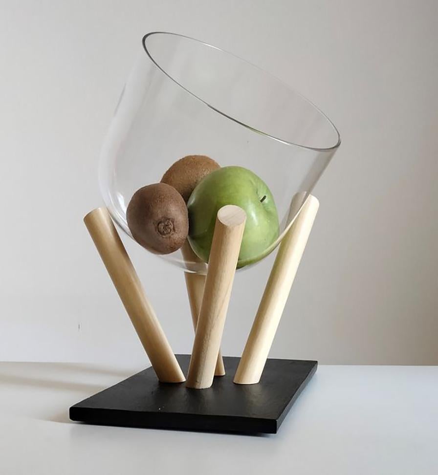 Fruit holder centrepiece consisting of a base in naturally split Ardesia stone from the Fontanabuona Valley with a wax finish and a mouth-blown glass fruit holder.
The bleached beech wood spacers allow you to tilt the fruit bowl in multiple
