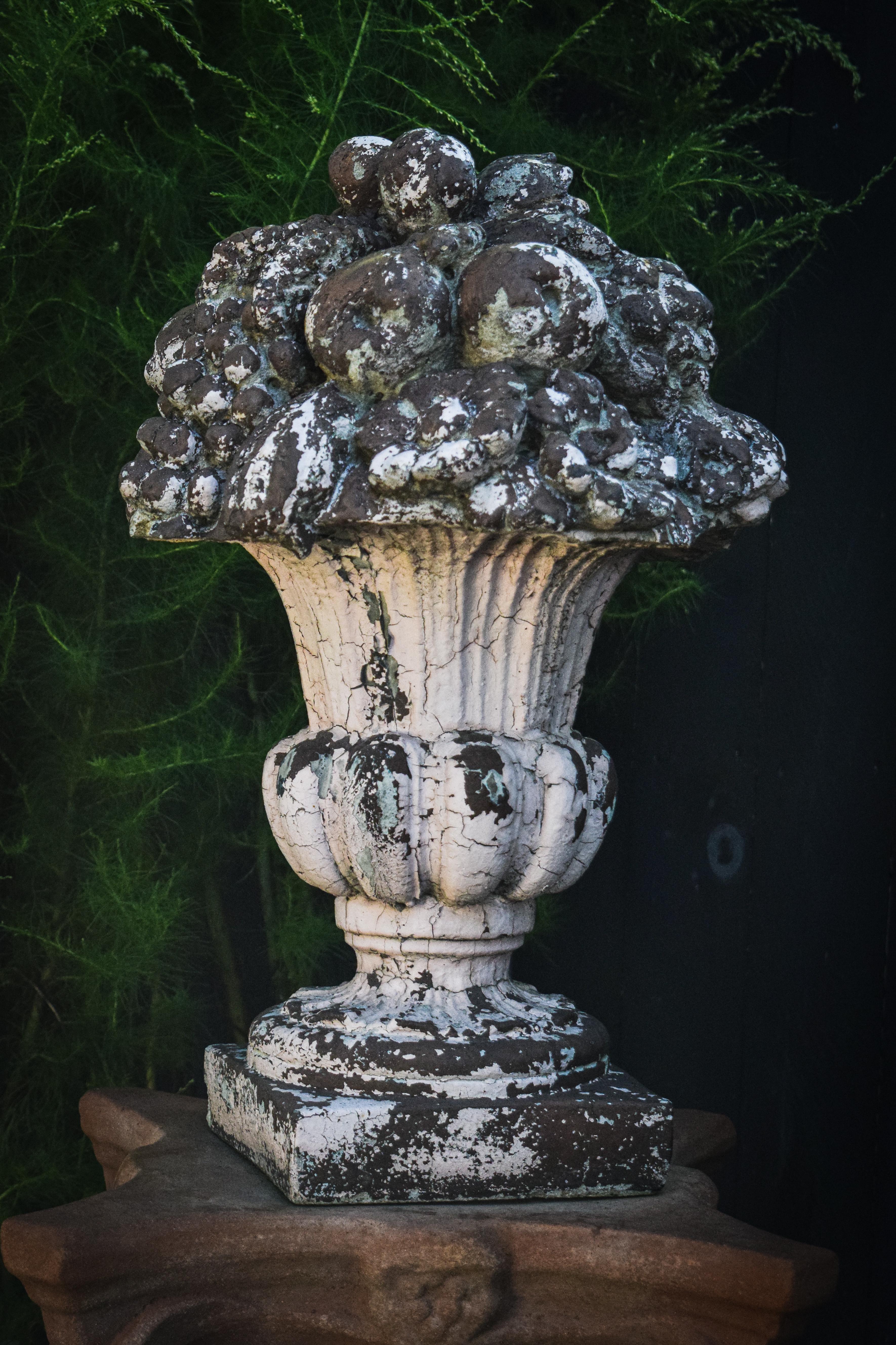 Brimming with fruit out of a traditional urn style base, this sculpture evokes a sense of long-standing abundancy. Looking pretty in vintage powder pink, each ornament is attractively patinaed with a one of a kind craquelure, allowing the composite