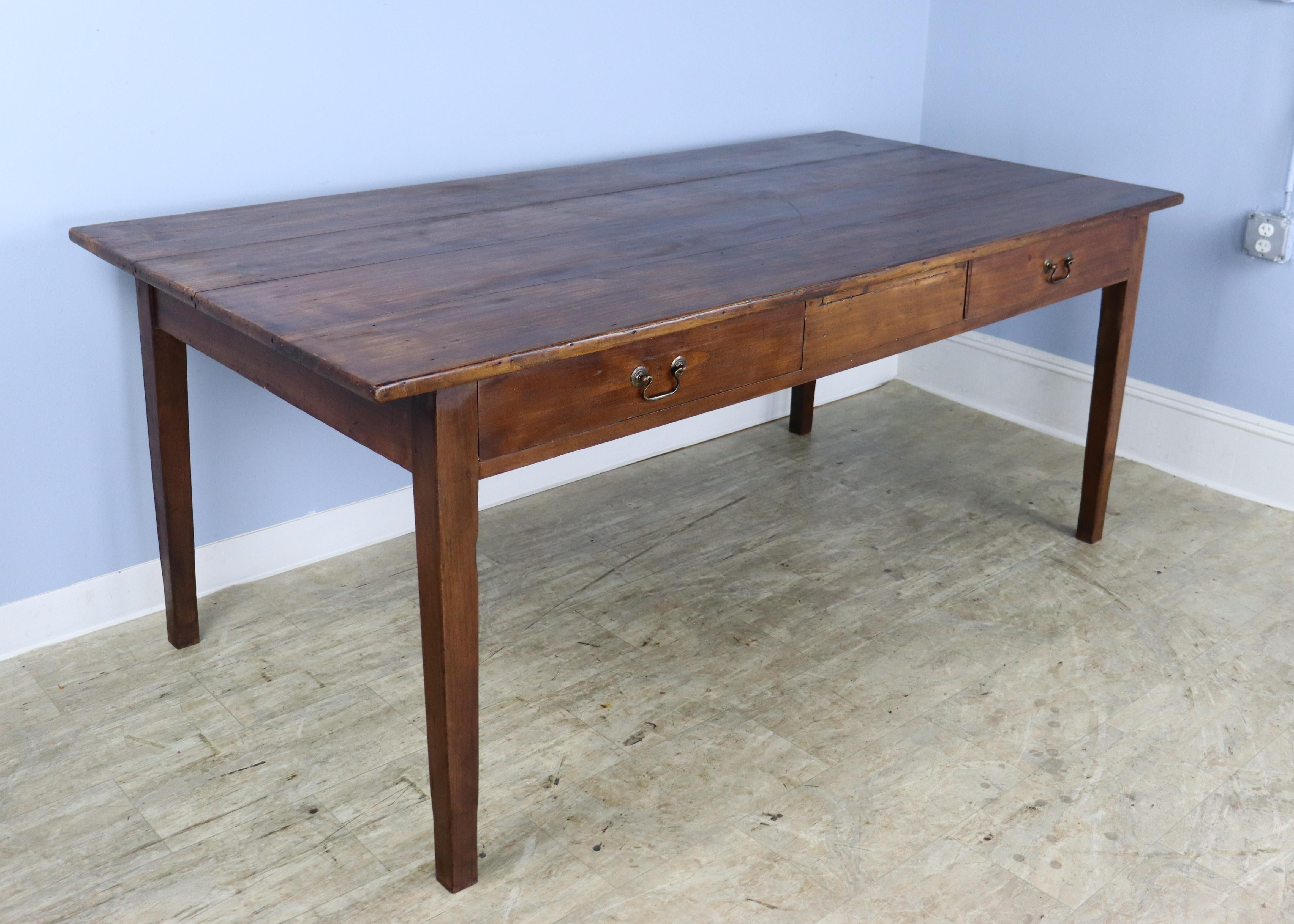 A small dining or farm table/desk in dark fruitwood with great depth, either for dining or for use as a partner's desk. Top has lovely grain and patina. 2 deep drawers on each side makes this a versatile choice. Classic tapered legs, nicely pegged