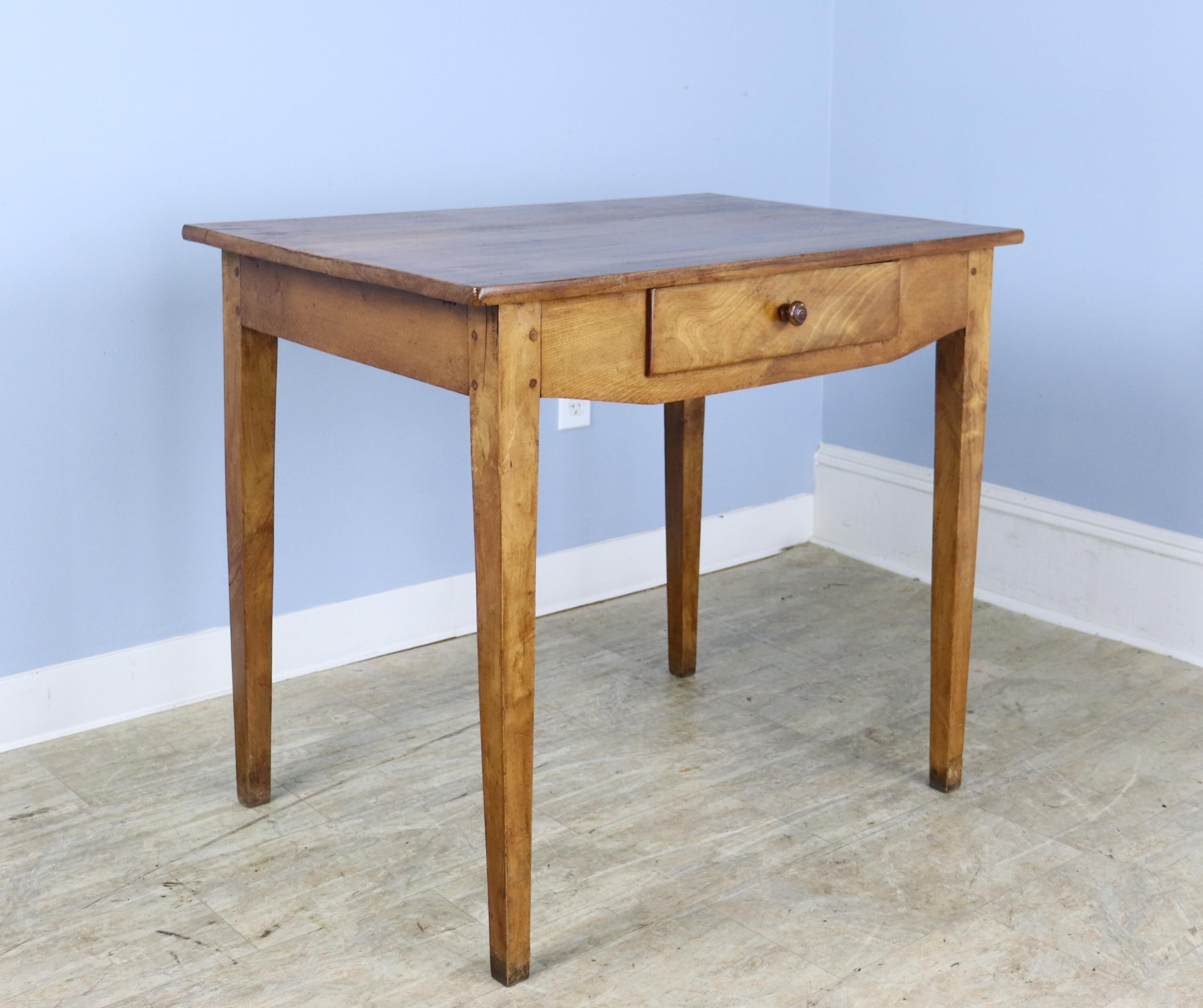 A simple and elegant fruitwood side table or small writing table/desk. The top has lovely grain and patina. Classic tapered legs, pegged at the apron. Single drawer for storage. The stylized front section has an apron height of 24.5 inches, and the