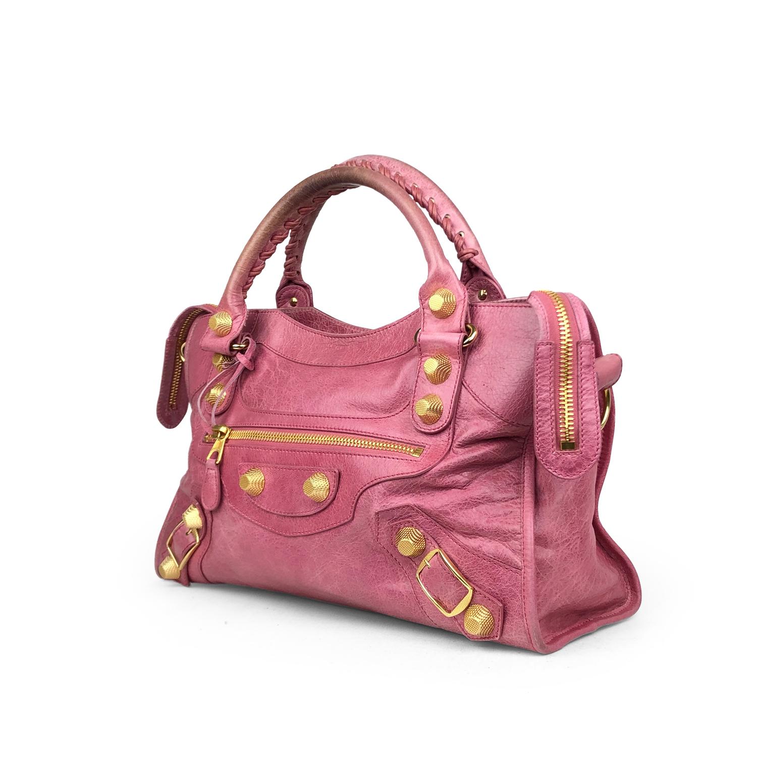 Fuchsia Arena leather Balenciaga Motocross City Bag with

– Gold-tone Giant 21 hardware
– Detachable shoulder strap
– Dual rolled top handles
– Exterior zip pocket, buckle and grommet embellishments, black woven lining, single zip pocket at interior