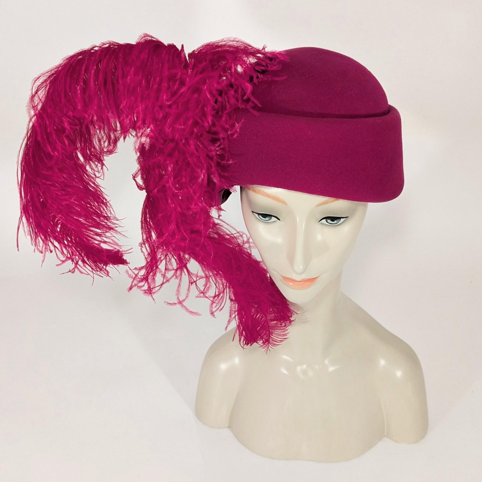 Questo favoloso cappello risale alla metà degli anni '80 ed è di un'incredibile tonalità di fucsia intenso. Le due piume sono molto grandi e si curvano magnificamente intorno al viso e al collo.