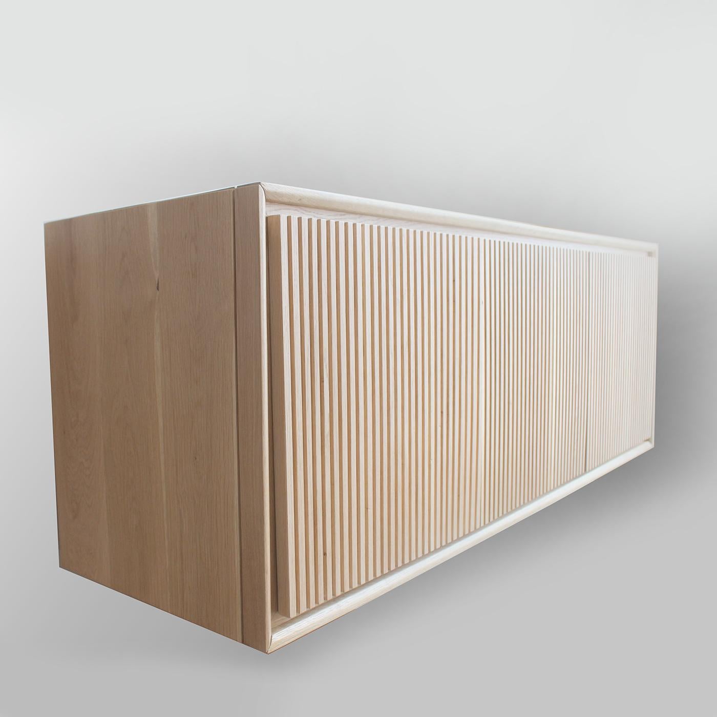 This elegant sideboard will make a sophisticated statement in any modern decor. It can be attached on the wall and float above the floor. Its simple silhouette is highlighted by the straight parallel lines that are carved vertically on the front