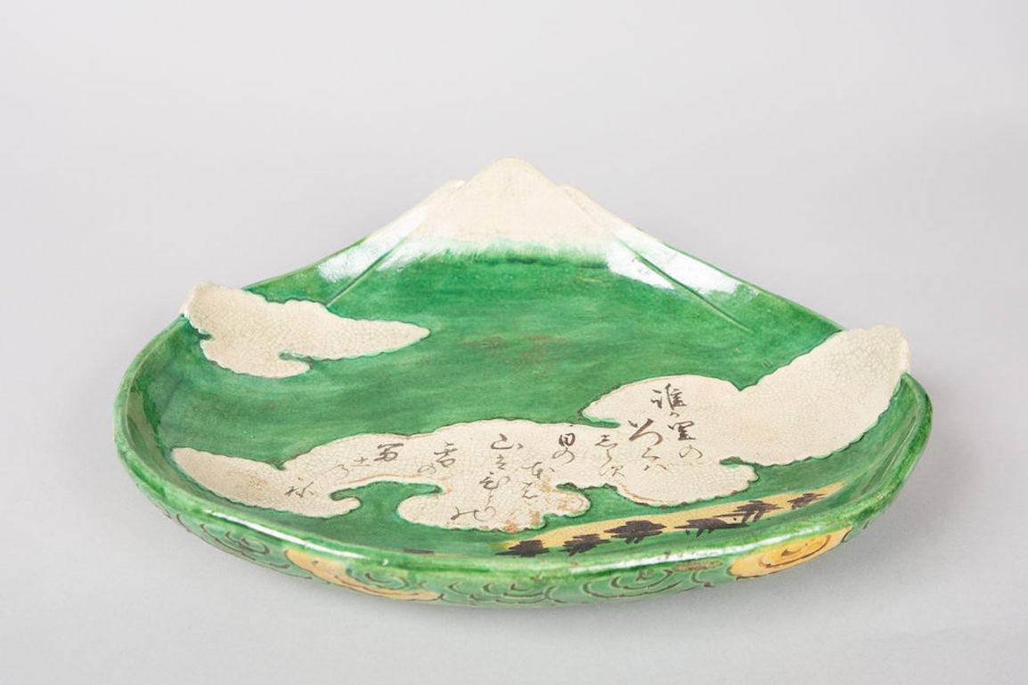 Fuji and Clouds, Showa Period (1926-1945) Kyotoware dish that is an ode to Mt. Fuji with clouds and a poem. Cloud design around the edges, and feet on the bottom. Poem loosely translates to: 
Whose hometown? I don't know where...
The place of the