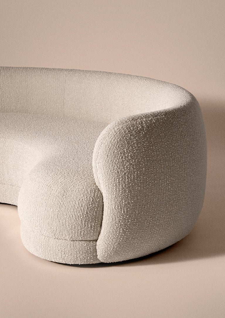 Rounded sofa upholstered in Dedar fabric, discrete plinth in wood. Featuring incredibly comfortable upholstery and soft structure made of non-deformable foam. All is crafted in France.