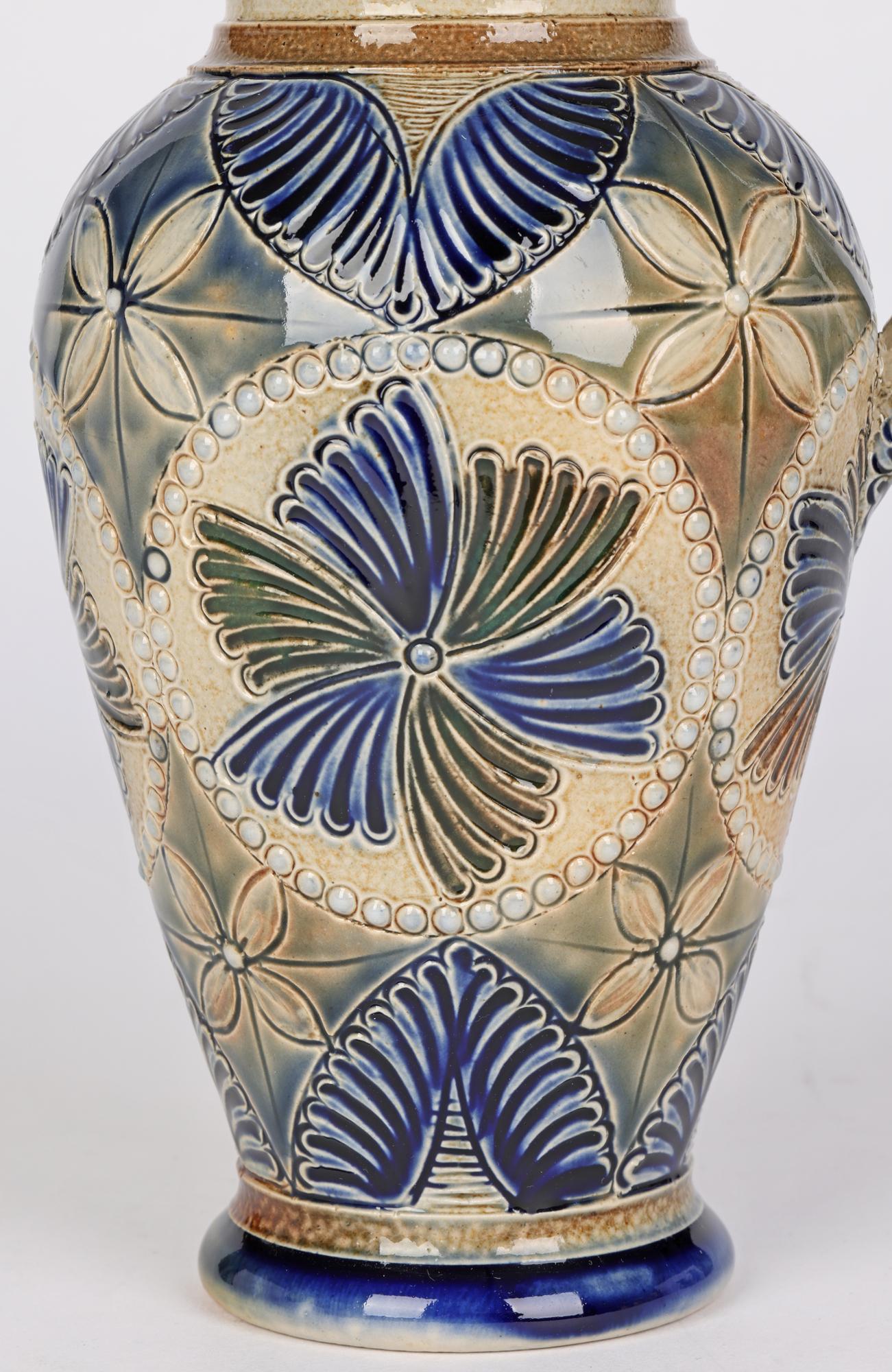 A good and finely decorated Aesthetic Movement stoneware jug decorated with fan shape and floral designs by John Pollard Seddon and dating from around 1880. The jug stands on a round foot with a tall bulbous shaped body and narrow funnel shaped neck