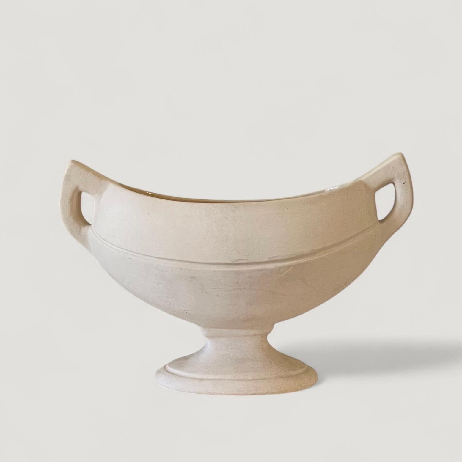 Un bellissimo due manici  vaso da camino con piede in terracotta bisquitica non smaltata con interno smaltato. Eseguito da Fulham Pottery, progettato da William Foster per la fiorista britannica Constance Spry. 

Impresso sul lato inferiore: Made in