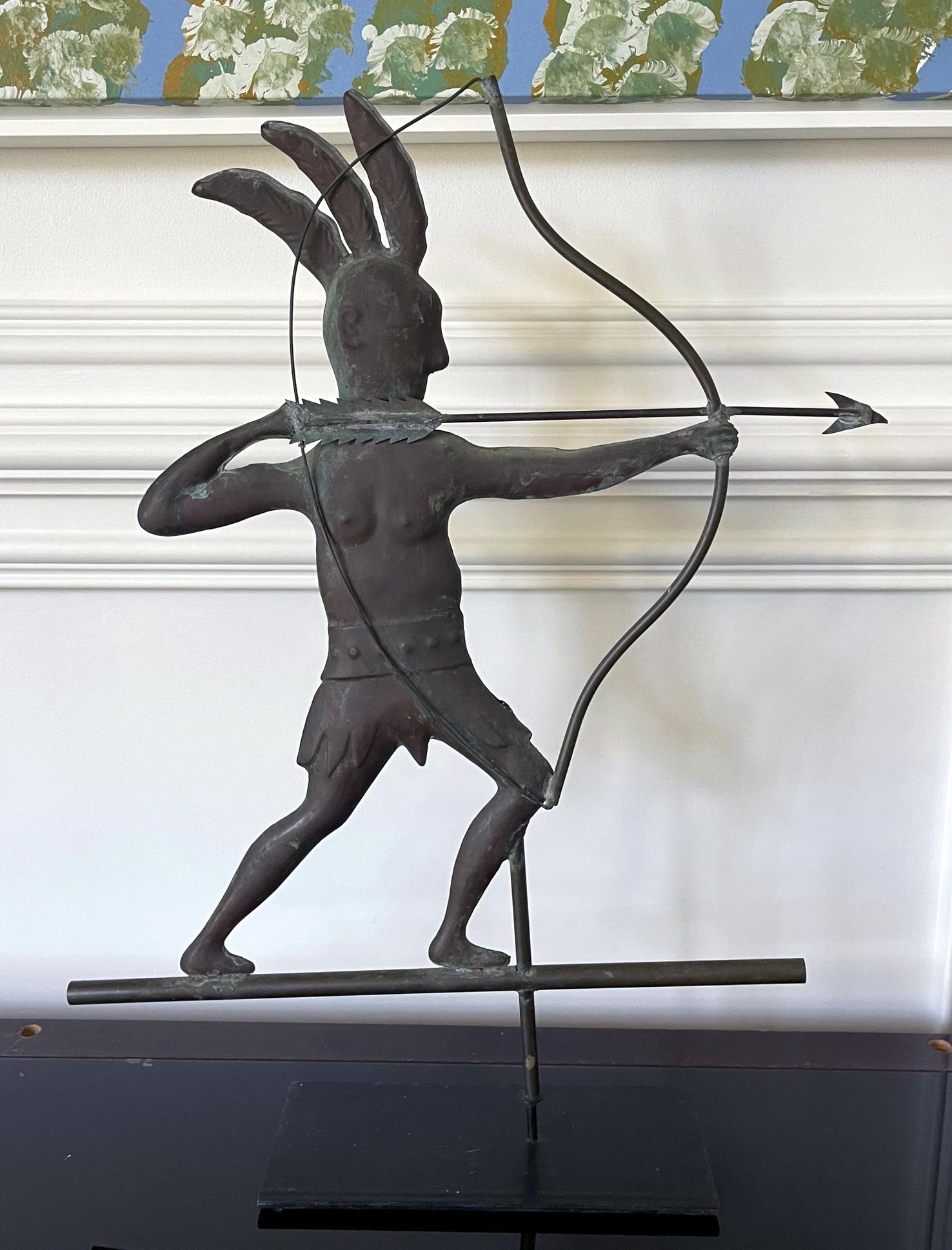 An Americana folk art copper weathervane circa early 20th century. The full-bodied piece depicts a Native American warrior in feather headdress and a wide belt shooting an arrow from his bow. The silouette showcases a strong graphic design and