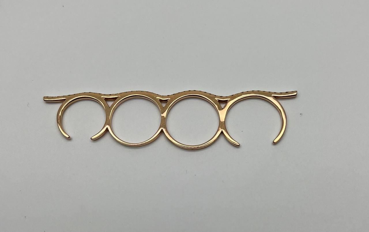 Cette pièce unique présente une série de formes circulaires interconnectées, fabriquées avec précision et portées sur quatre doigts et sur toute la main. Cet accessoire présente une esthétique élégante et moderne avec une finition polie. Parfait