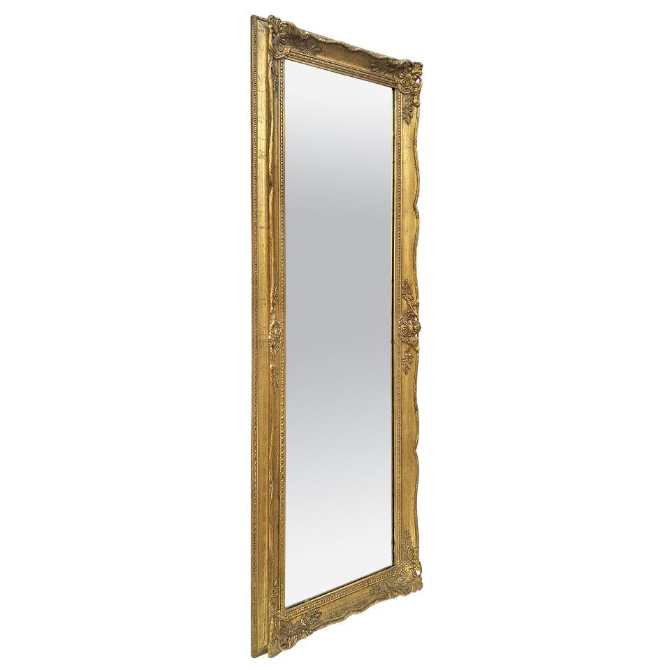 Full-length giltwood wall mirror with French decor Louis XV style, circa 1960. Carved gilt wood frame (width: 6.5 cm / 2.55 in.) made in belgium (Provenance label on the back). Modern glass mirror. Hardboard (masonite) and painted wood at the back.