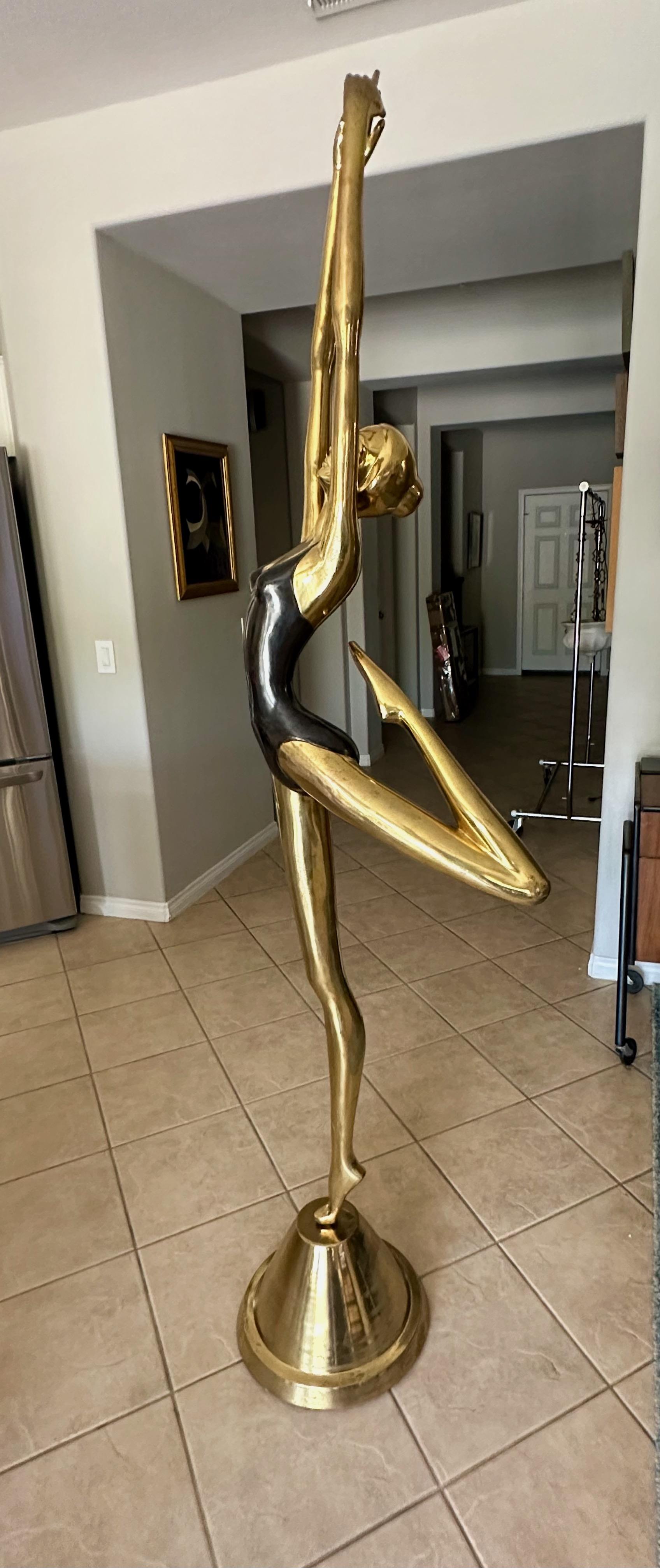 Over 6 ft tall is an inspiring and graceful stylized brass and partially black patinated ballerina dancer statue on a brass dome shape stand. Her elegant facial expression and graceful elongated arms and legs are reminiscent of Alberto Giacometti. 