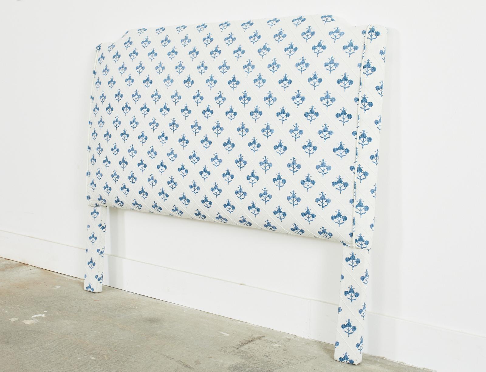 Stylish full sized padded headboard redux featuring a block print blue and white linen style upholstery with a geometric diamond pattern background. The print design is decorated with indigo blue floral sprays in an aged patina. The vintage