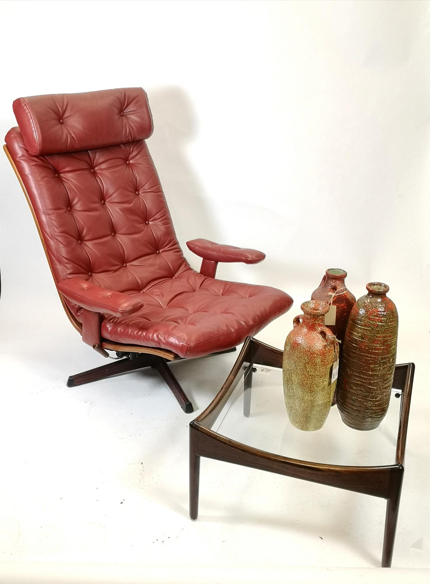 This cognac colored full leather lounge or easy chairs swivels and it's adjustable. It was designed by Göte Design in Sweden, Nässjö, 1960s.
It features a massive palisander adjusting handle and a palisander print on the base. It features the