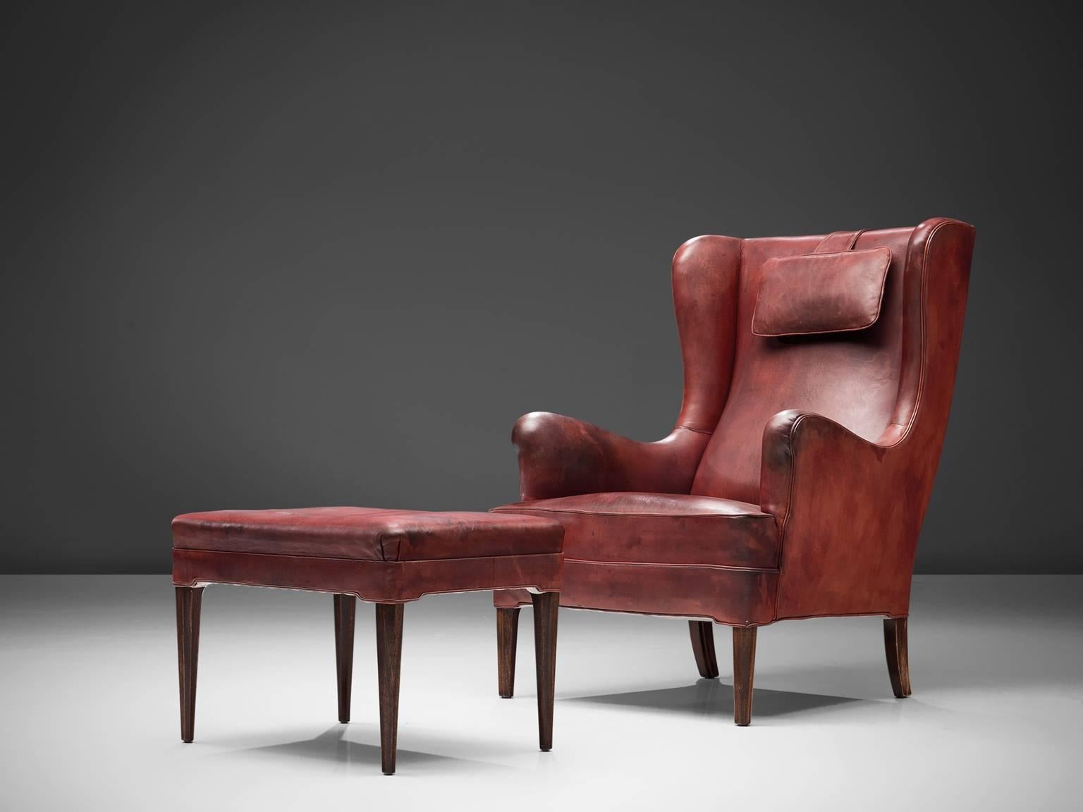 Frits Henningsen, wingback chair and ottoman, red cognac leather and wood, by Denmark 1940s. 

Classical wingback chair with accompanying footstool in patinated cognac leather. This chair and ottoman hold their original cognac leather upholstery.