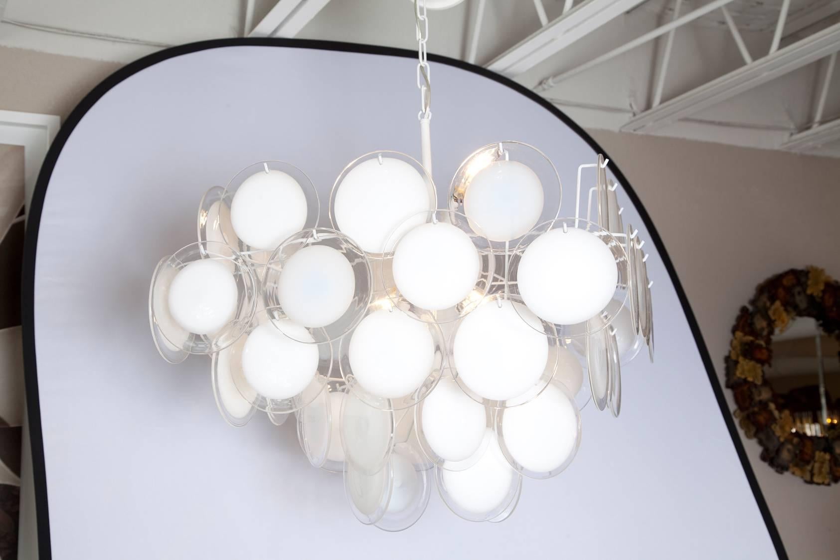A fully restored, nicely scaled 1970s Vistosi chandelier with clear handblown Murano glass discs with white centres, hung on a newly re-wired, fresh white metal frame. Additional 18 inches of chain and canopy.