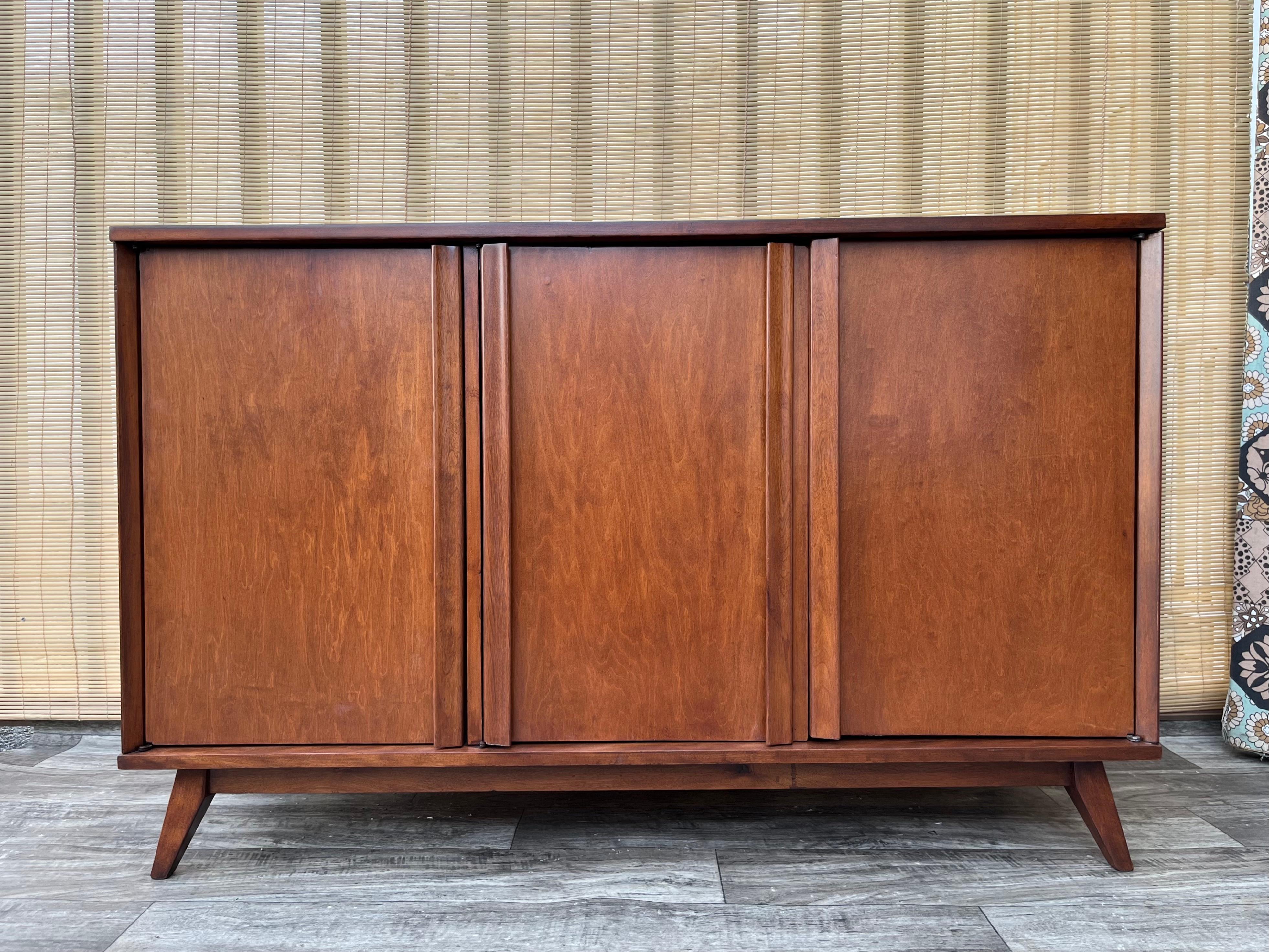 Fully Restored Mid Century Modern Sideboard Credenza. Circa 1960s.
Features a sleek Mid Century Modern design with tapered legs, a solid wood body, four hidden drawers, and a two doors cabinet with fixed shelves for extra storage space. 
Recently