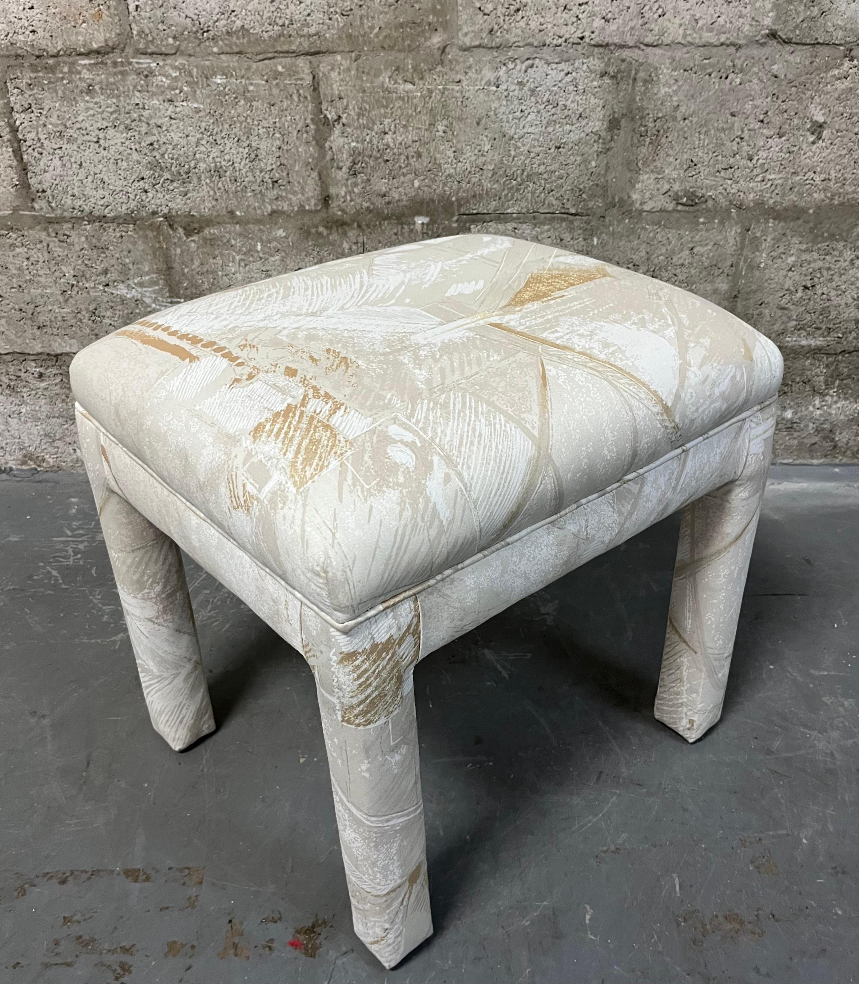 Vintage Fully Upholstered Postmodern Parson Style Vanity Bench Stool. Circa 1980s
Features a completely upholstered body with a fabric with beige, antique gold, and tan abstract print on a solid soft cream background. 
With near mint original