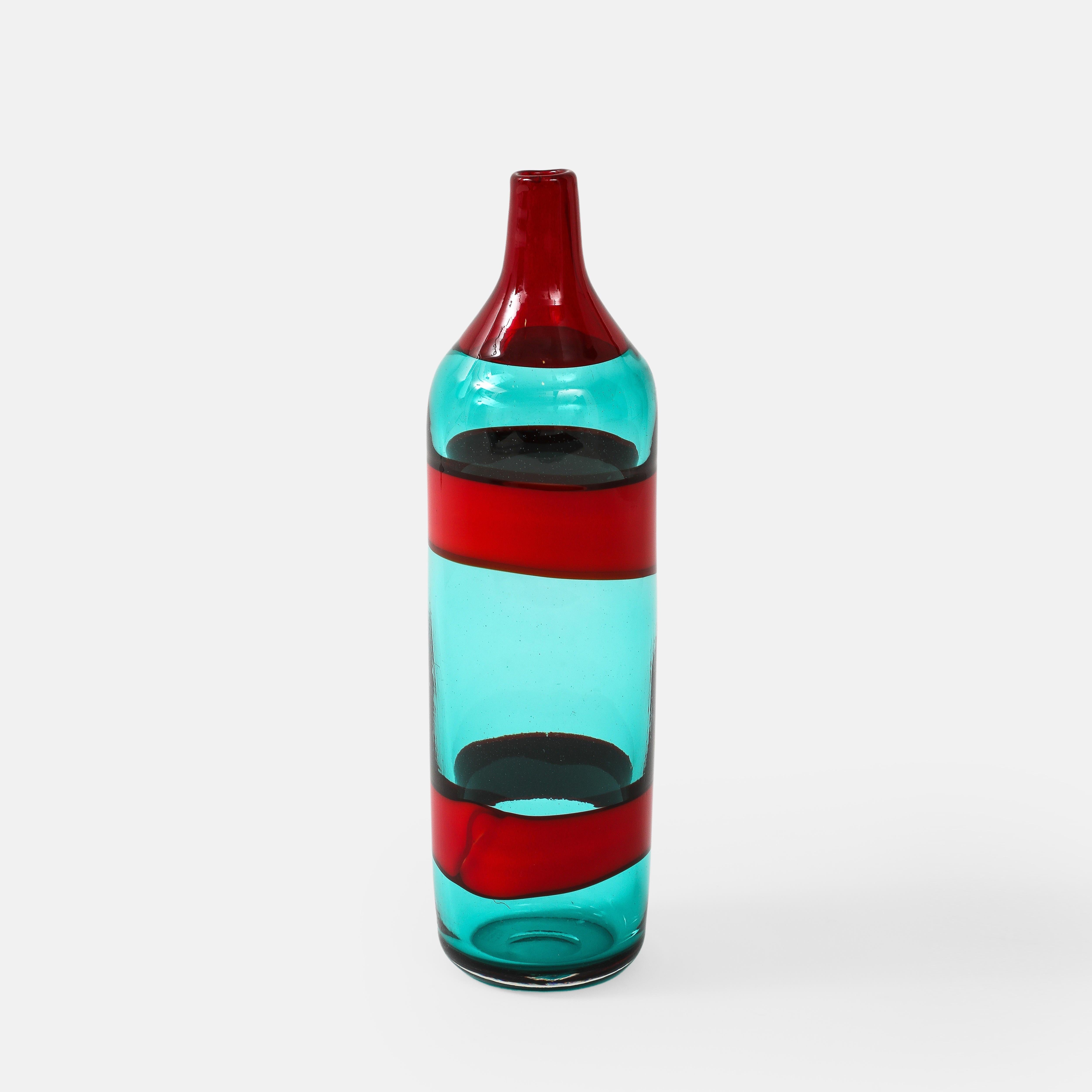 Fulvio Bianconi for Venini Fasce Orizzontali large bottle model 4315 in transparent blue green glass decorated on the body by two horizontal bands in opaque red and on the neck by a single transparent red band, Italy, circa 1950.  Although simple in