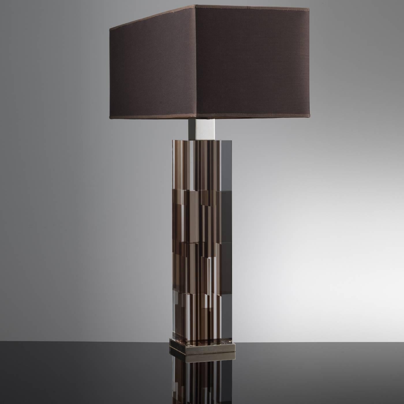 The body of this exquisite lamp is made of a complex structure of squared and rectangular Lucite pieces in brown and transparent finishes. The effect is a single block that changes color and design depending on the point of view. The top and bottom