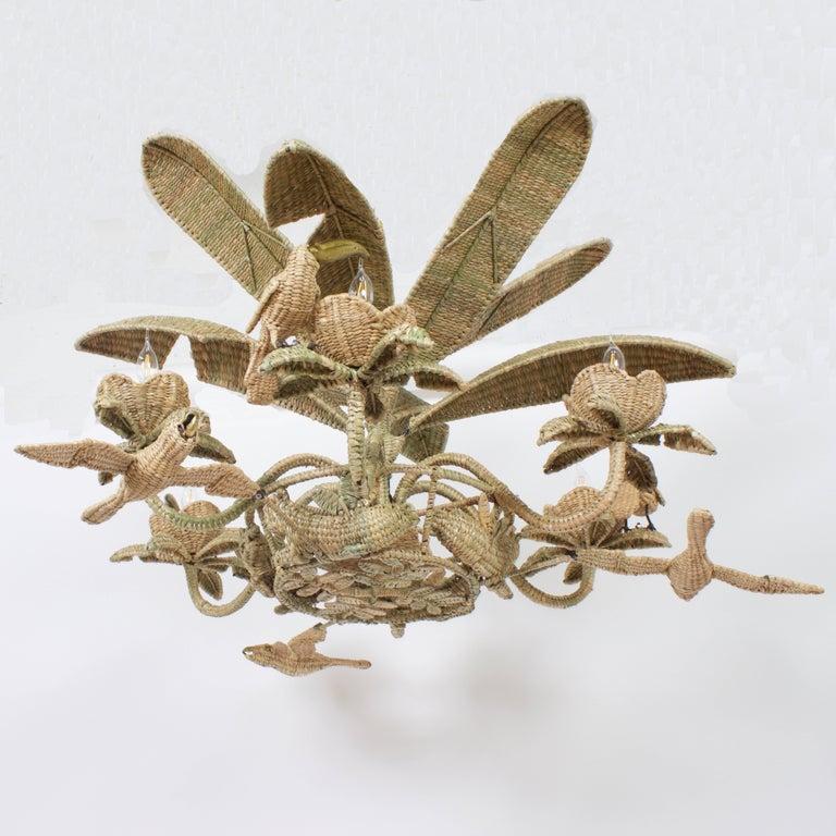 Fun and folky Mario Torres animated wicker or reed chandelier. Constructed with an iron frame wrapped with wicker and depicting Toucans, parrots, panthers and palm leaves. Perfect for island, coastal, and tropical homes or any interior that deserves