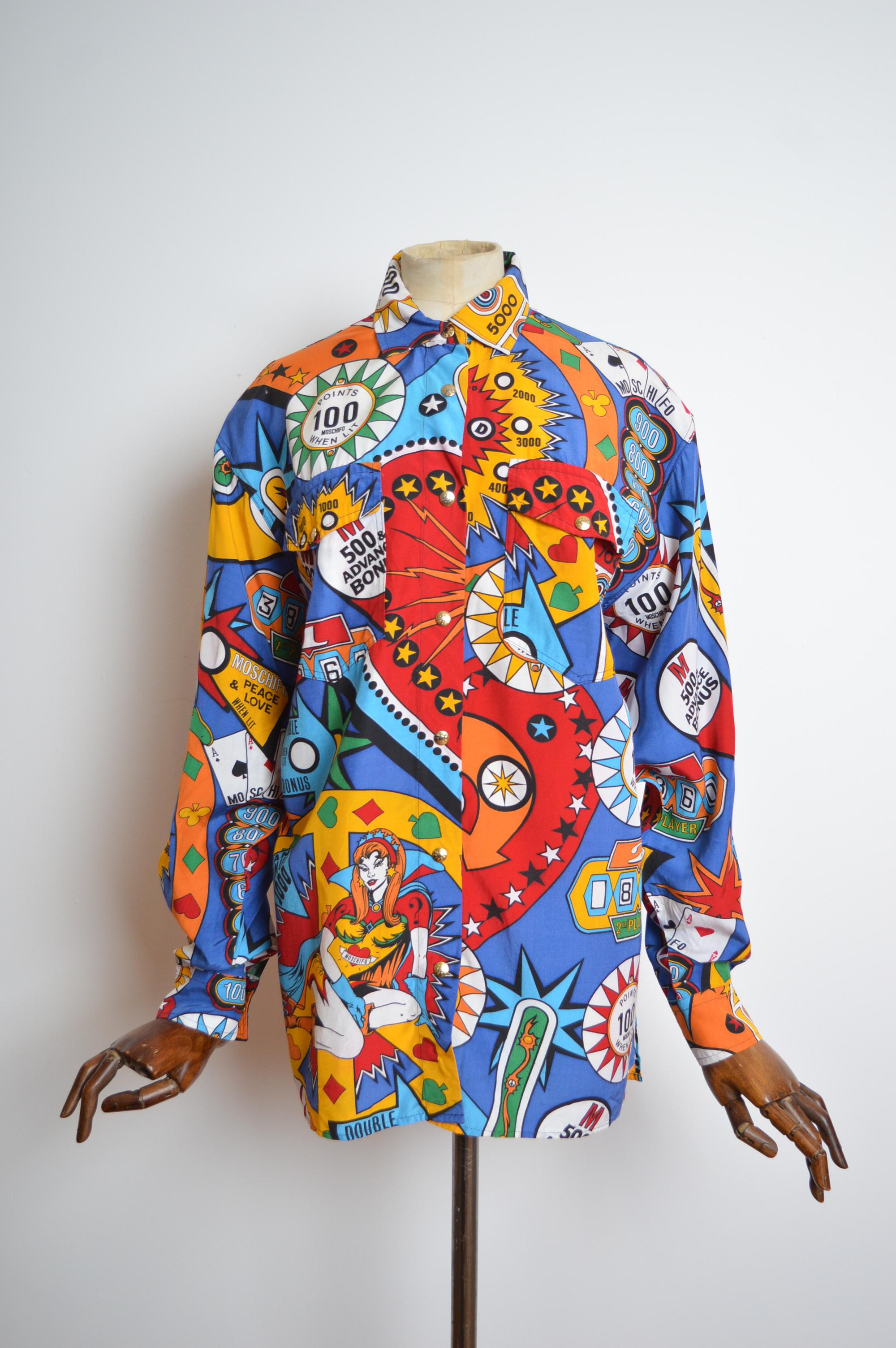 Chemise à imprimé Loud Colourful des années 1990 à thème Casino Pinball de Moschino, en rouge.
FABRIQUÉ EN ITALIE 
100% Rayon 
Boutons dorés sur le devant / Poches poitrine / Coupe ample / Manches longues 
De la fosse à la fosse ; 24
