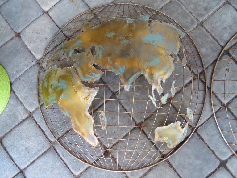 Fun Curtis Jere designed brass two piece world map wall sculpture. A finely rendered handmade two-piece wall-mounted sculpture depicting the continents of the earth, crafted of warmly patinated brass with traces of verdigris. This piece measures