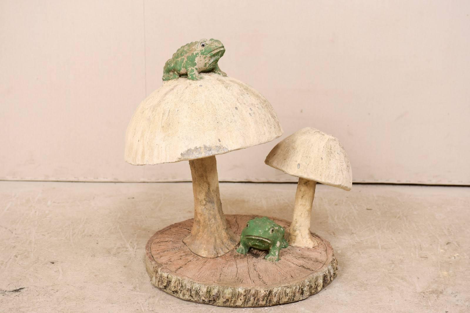 A whimsical midcentury garden sculpture depicting a pair of mushrooms and frogs atop a faux bois slab base. This folk art piece originated from Texas during the mid-20th century. This frog and mushroom themed vintage garden statuary stands at over 2