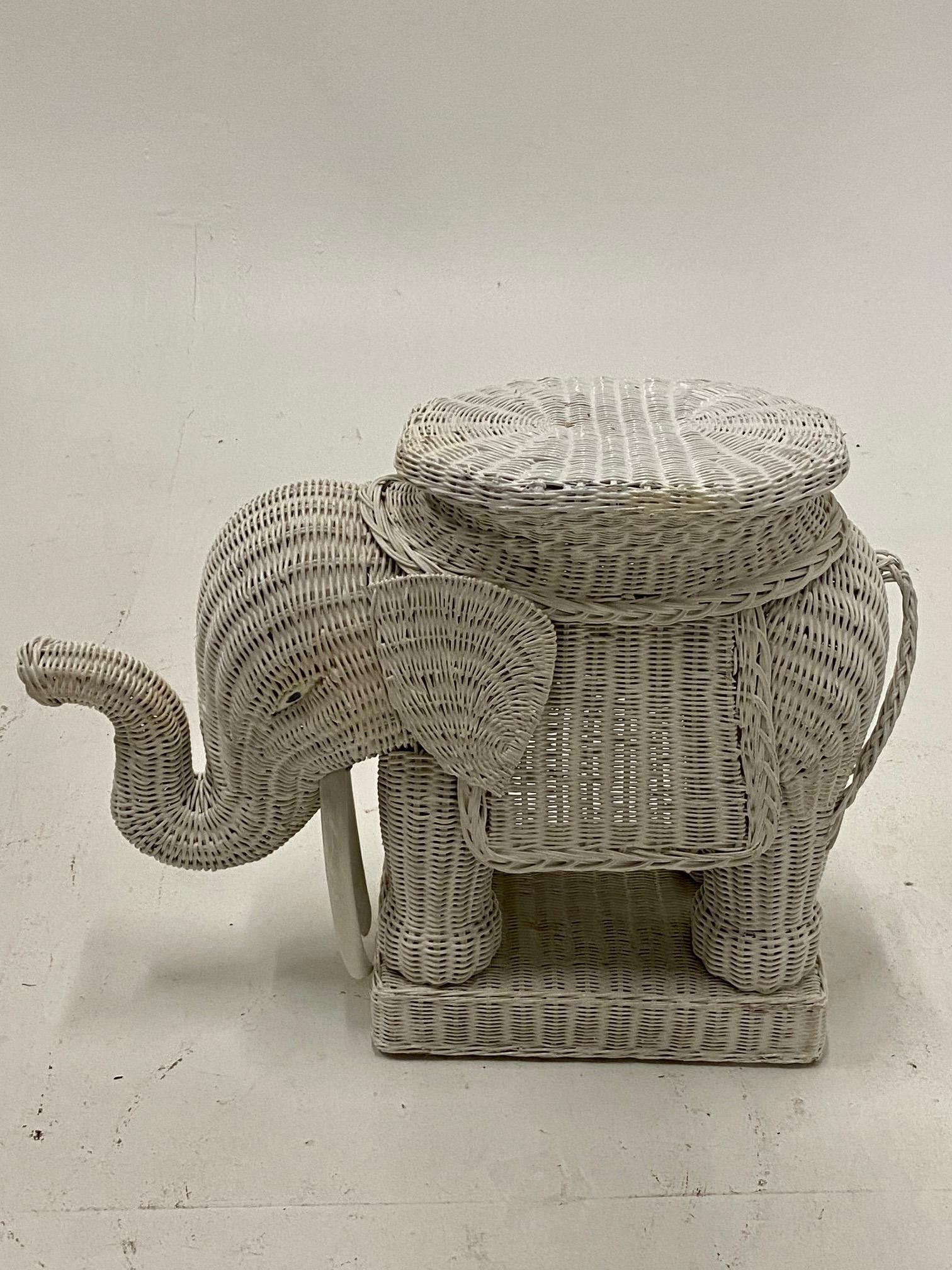 An adorable vintage white painted woven wicker, rattan and wood drinks table in the shape of an elephant having the trunk in the lucky upward position with long tusks beneath.