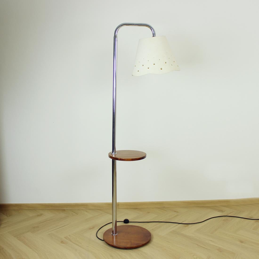 Magnifique lampadaire autoportant art déco produit par Up&Up Zavody en Tchécoslovaquie, conçu par Jindrich Halabala. La lampe repose sur une simple base en bois qui supporte une solide tige en acier chromé. Il y a une étagère en bois sur la lampe.