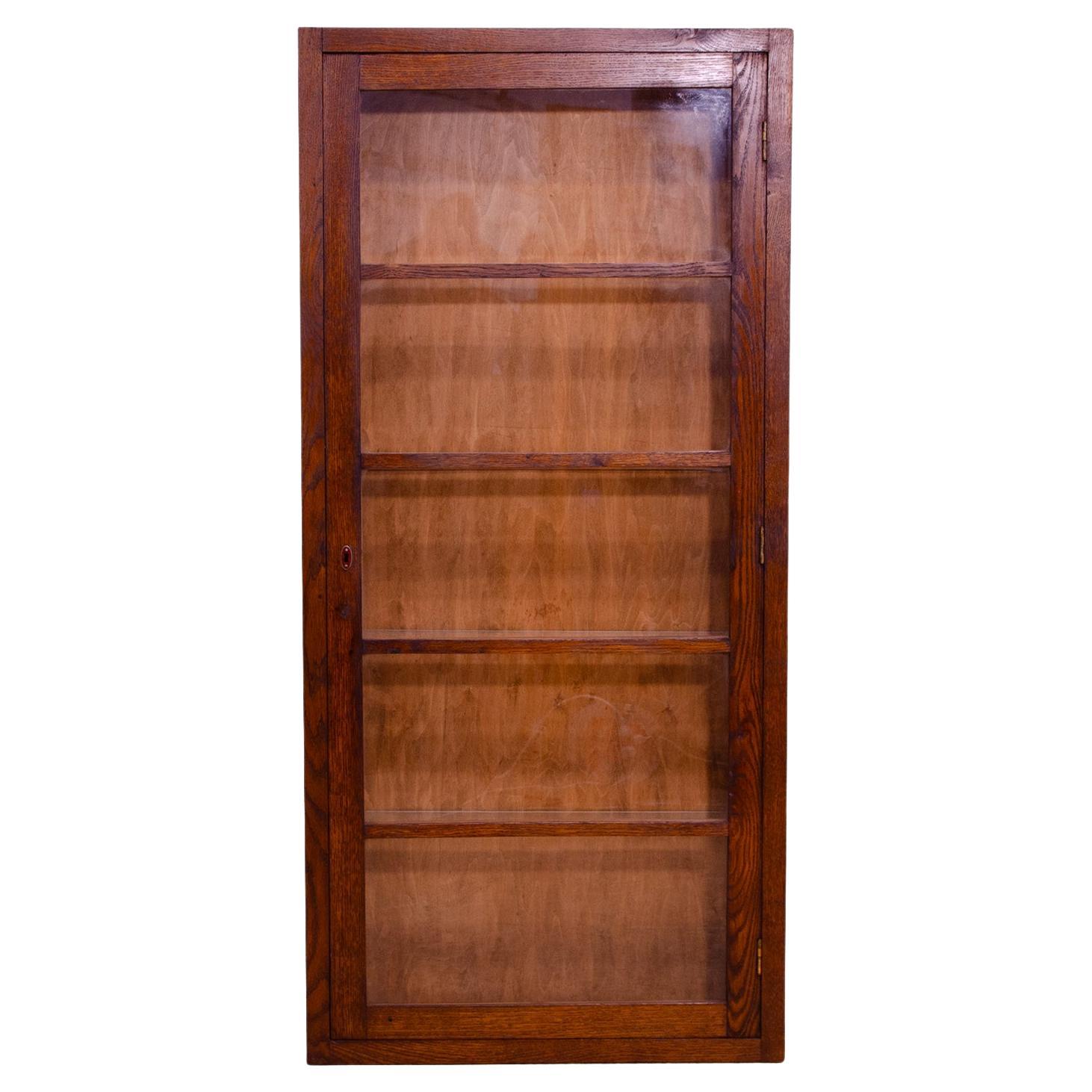 This narrow Functionalism display case was produced in the 1930s in the former Czechoslovakia. Material oak. The showcase is very practical and easy to handle due to its dimensions. It is also suitable as a bookcase, it can be placed in the space.