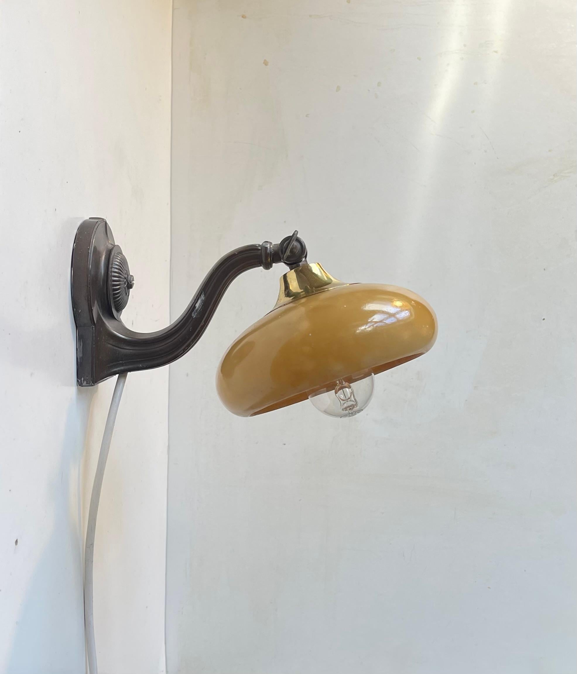 A 1940s small bedside table lamp or wall light. Featuring a patinated metal base and an adjustable honey colored alabaster stone shade giving it a very special and tactile look especially when lid. It was made, possibly bespoke, in either Italy or