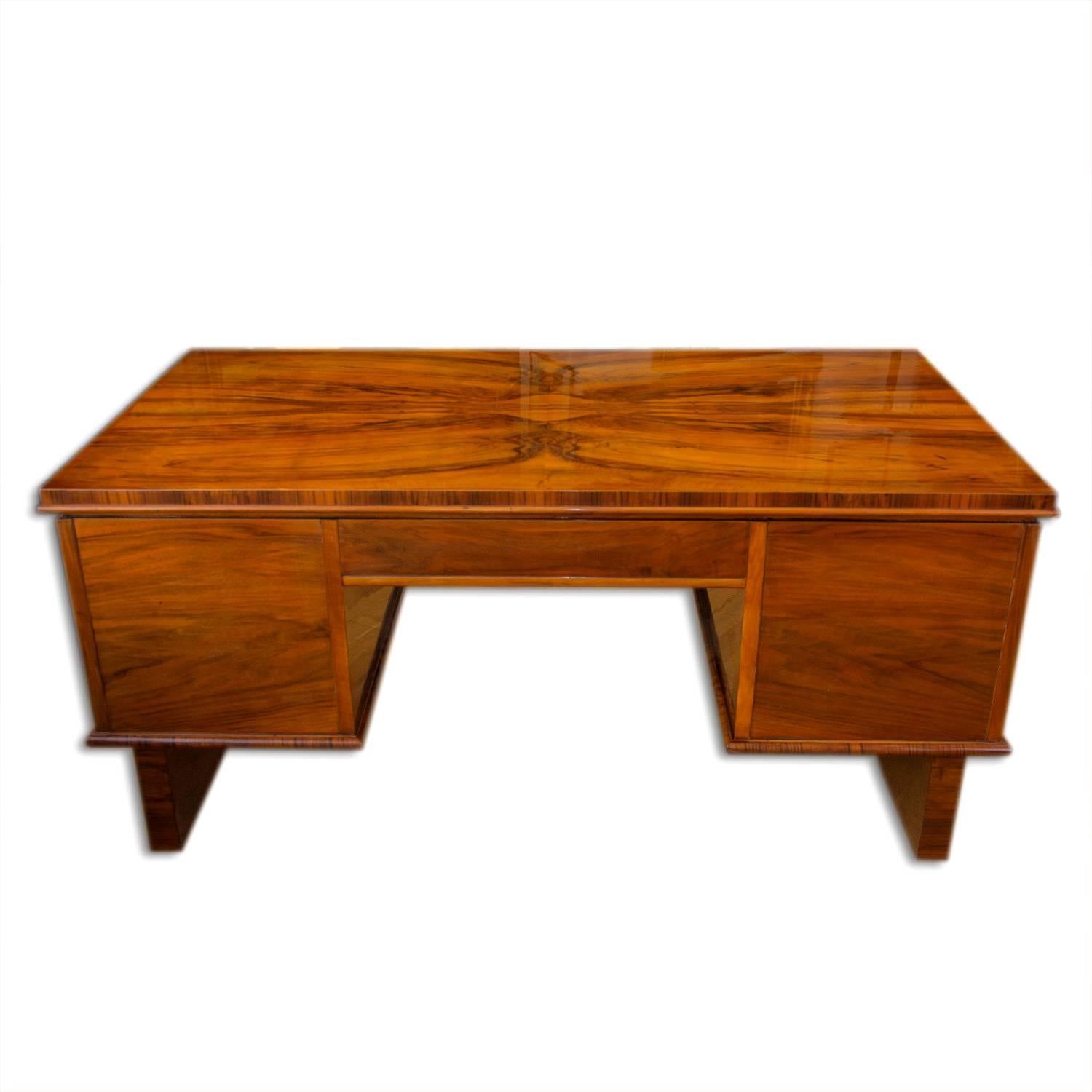 This functionalistic desk was made in the 1930s in Bohemia. It is veneered with walnut veneer, features six drawers. Its shape is dominant due to its high standing legs, thanks to which it can be used spatially. The table is in excellent condition