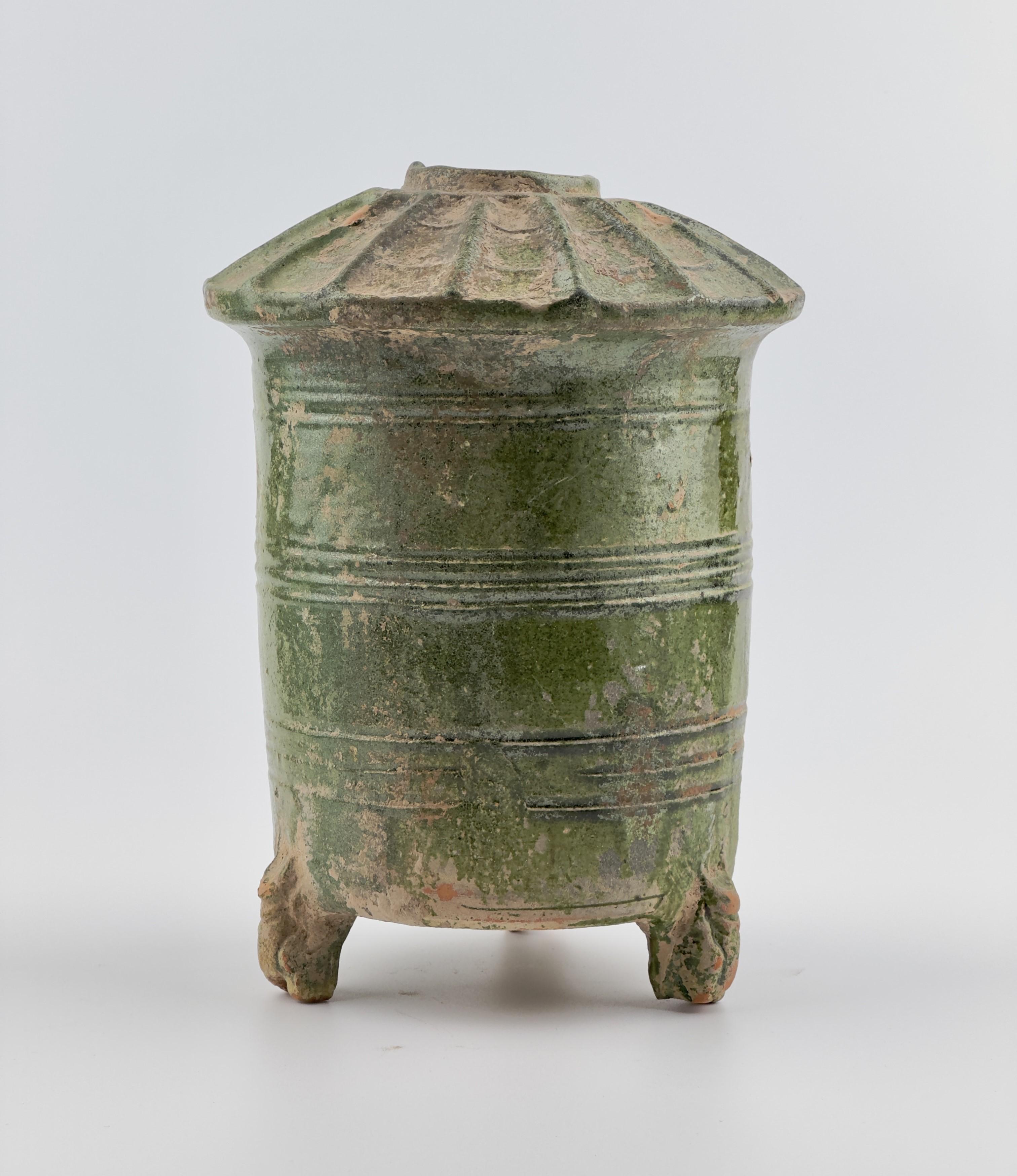 Cylindrical vessel on three animal-shaped feet (dragon or snake), wall with profile grooves, roof. pottery with green lead glaze. 