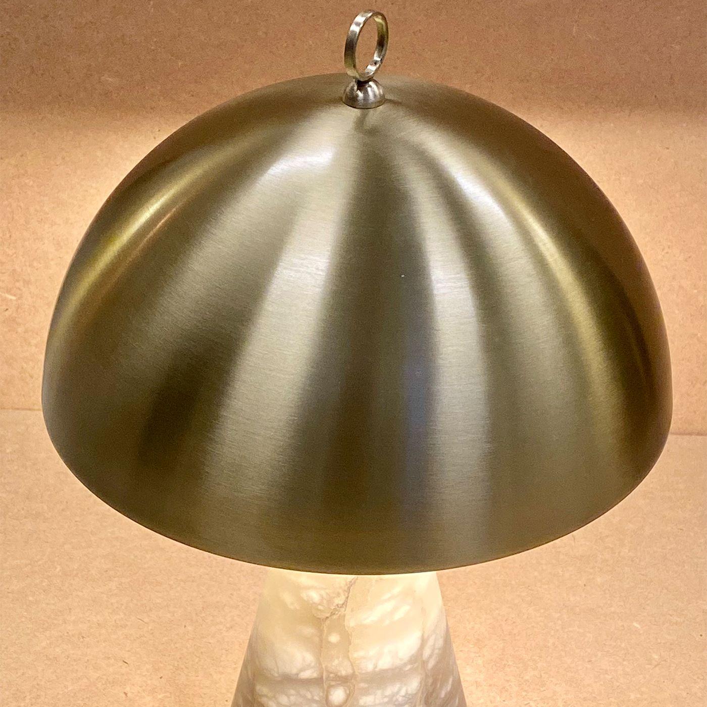 A small and compact table lamp composed of a conic alabaster base with a hand-lathered brass cover. It is suitable for bedside tables and wall cabinets. It is also available with inverted base and cover materials to match in the same ambience.
