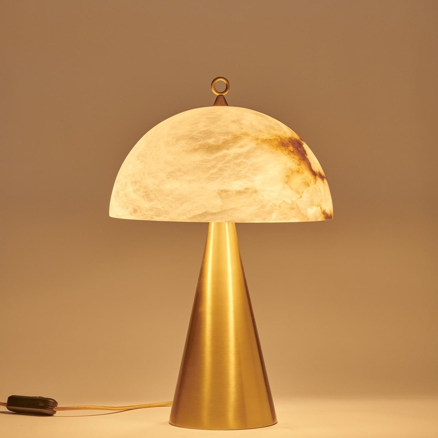 Née du succès de notre modèle Funghetto, la lampe de table Fungotto présente des dimensions plus grandes et plus audacieuses, tout en conservant la simplicité de ses formes. L'abat-jour semi-sphérique en albâtre, dont les veines sont soulignées par