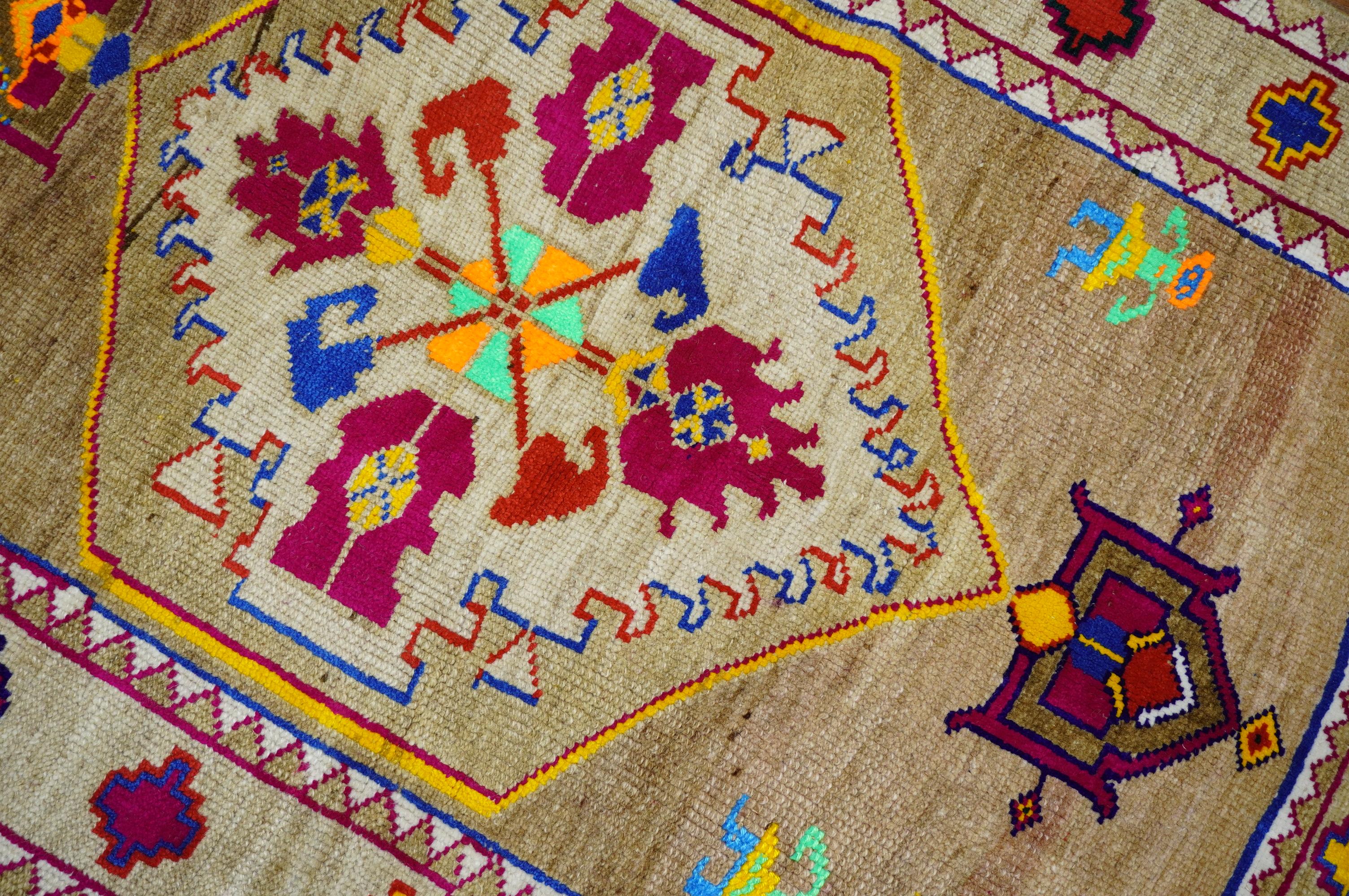 A one of a kind Boutique looking hand knotted scatter size vintage Turkish rug featuring bright cotton accents in dominant orange, yellow, violet orange blue and neon green on a brown field hovered by a large medallion and 2 humans. The accent