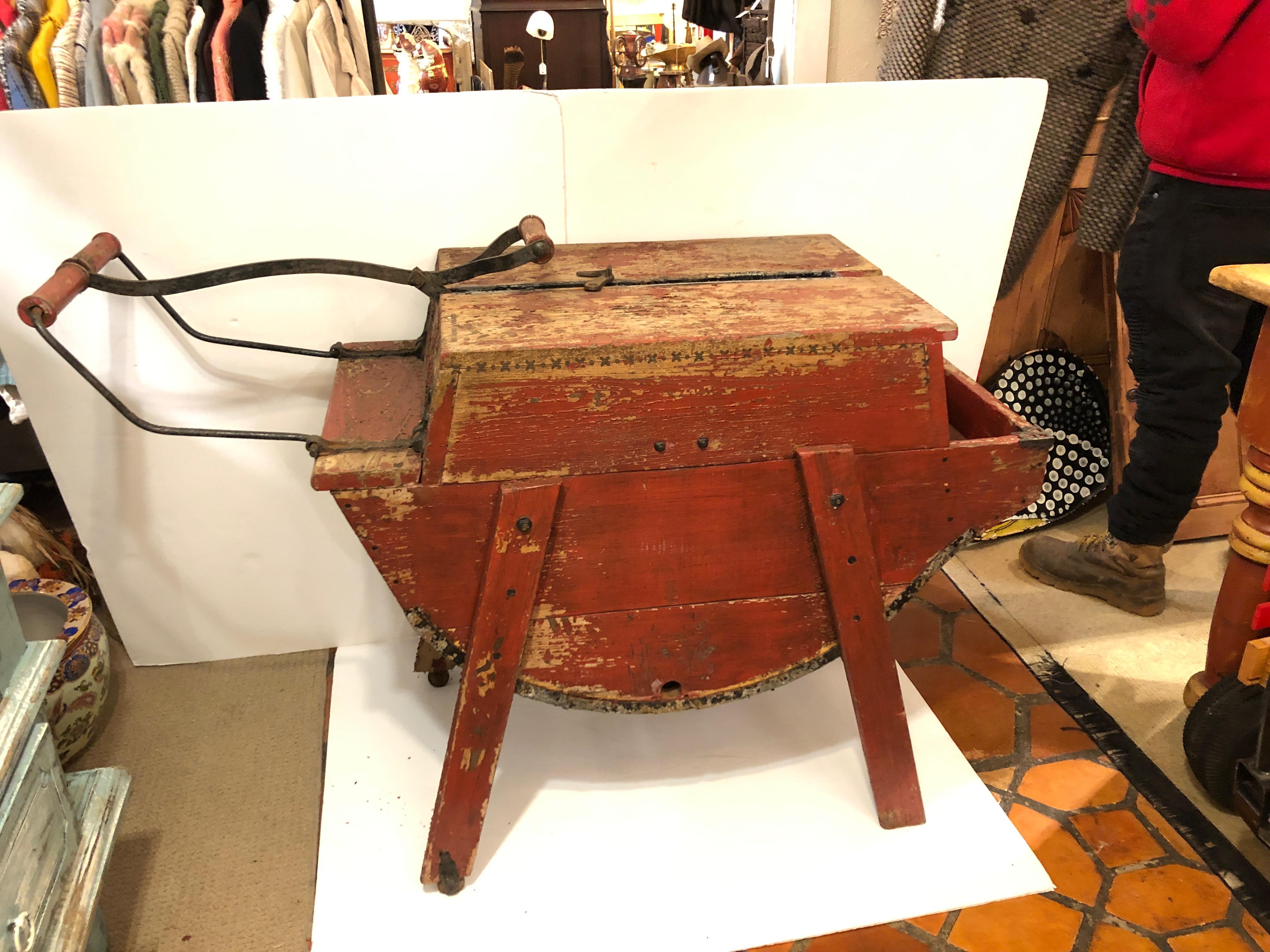 A fabulous vintage weathered red wooden washing machine that someone with imagination can use as a side table or found object that adds warmth and curiosity to a space.
Handle on left lifts up and down, protrudes 13