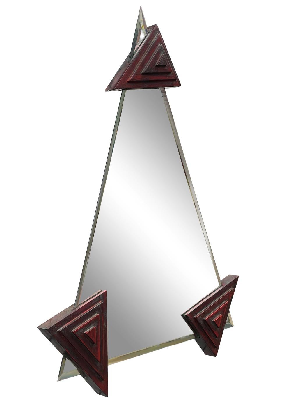 An eye catching post modern design mirror from Italy circa 1980s. It features a floating mirror design with stacked triangular brackets in red and gray.