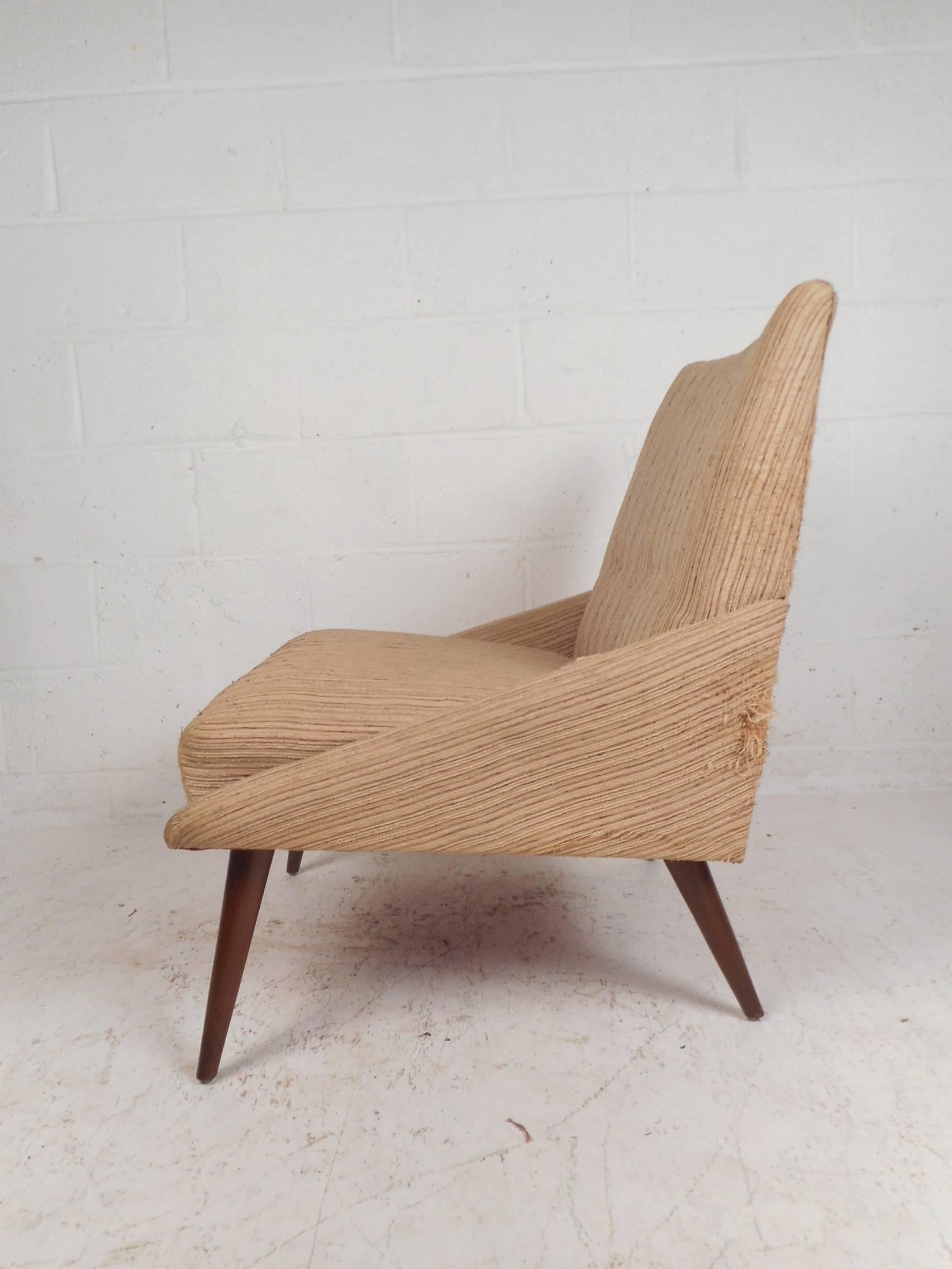 This unique vintage modern lounge chair features angled sides and splayed lets. Sleek design with a thick padded seat upholstered in plush beige fabric. This stylish and comfortable lounge chair makes the perfect addition to any seating arrangement.