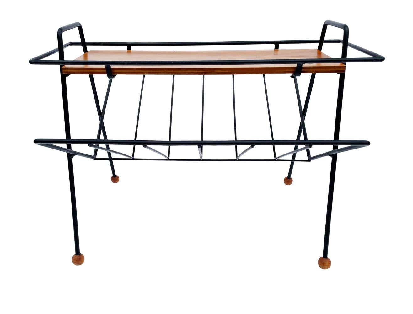 An uncommon magazine rack / table designed by Tony Paul circa 1950's. It features black metal framing with maple wood accents.