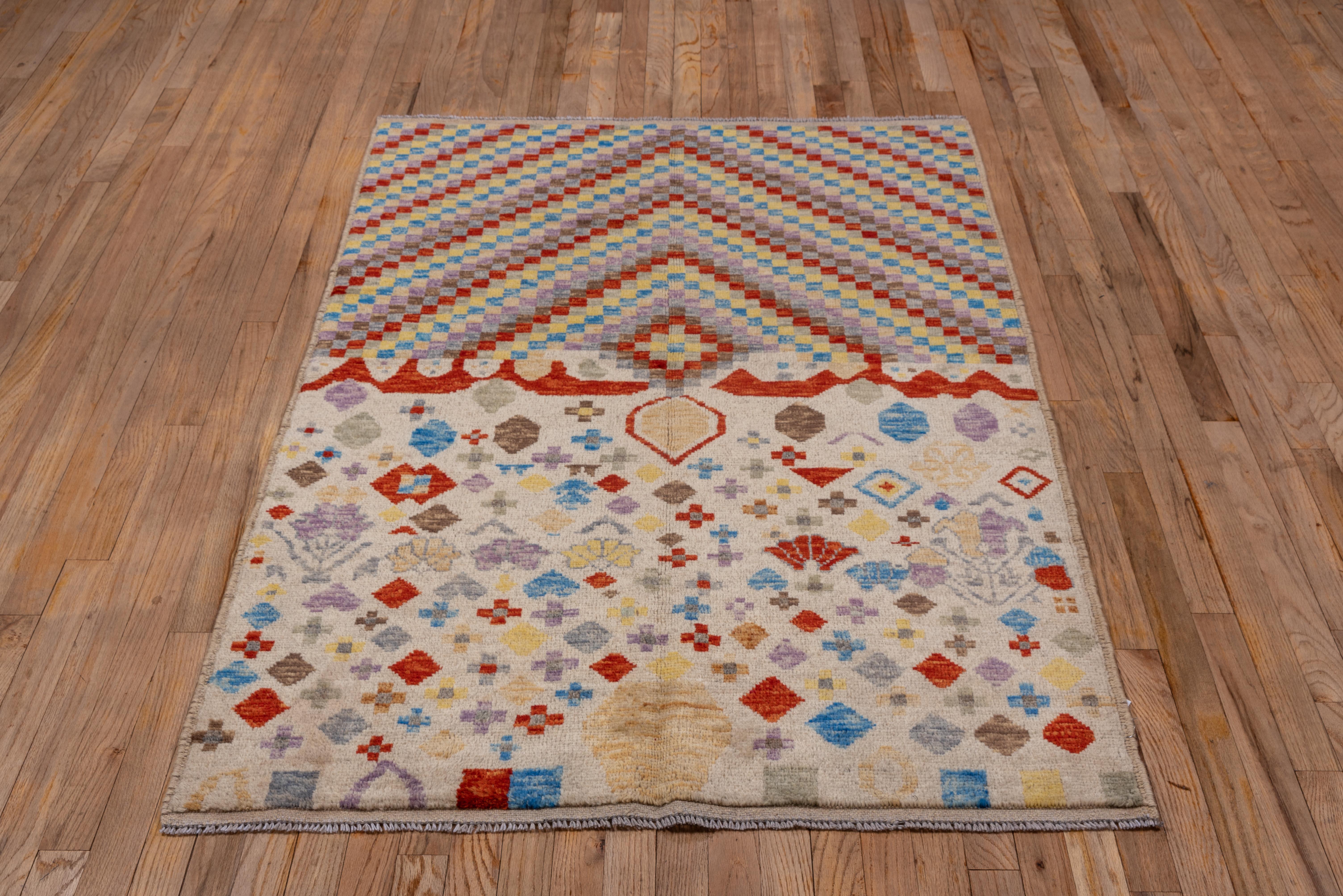 This modern Gabbeh rug has one half is cream grounded, with a scatter of crosses, small hexagons, detailed flowers and wriggling cloud bands, all in closely abrashed red, light blue, straw, light green and rose. The other half displays a chevron