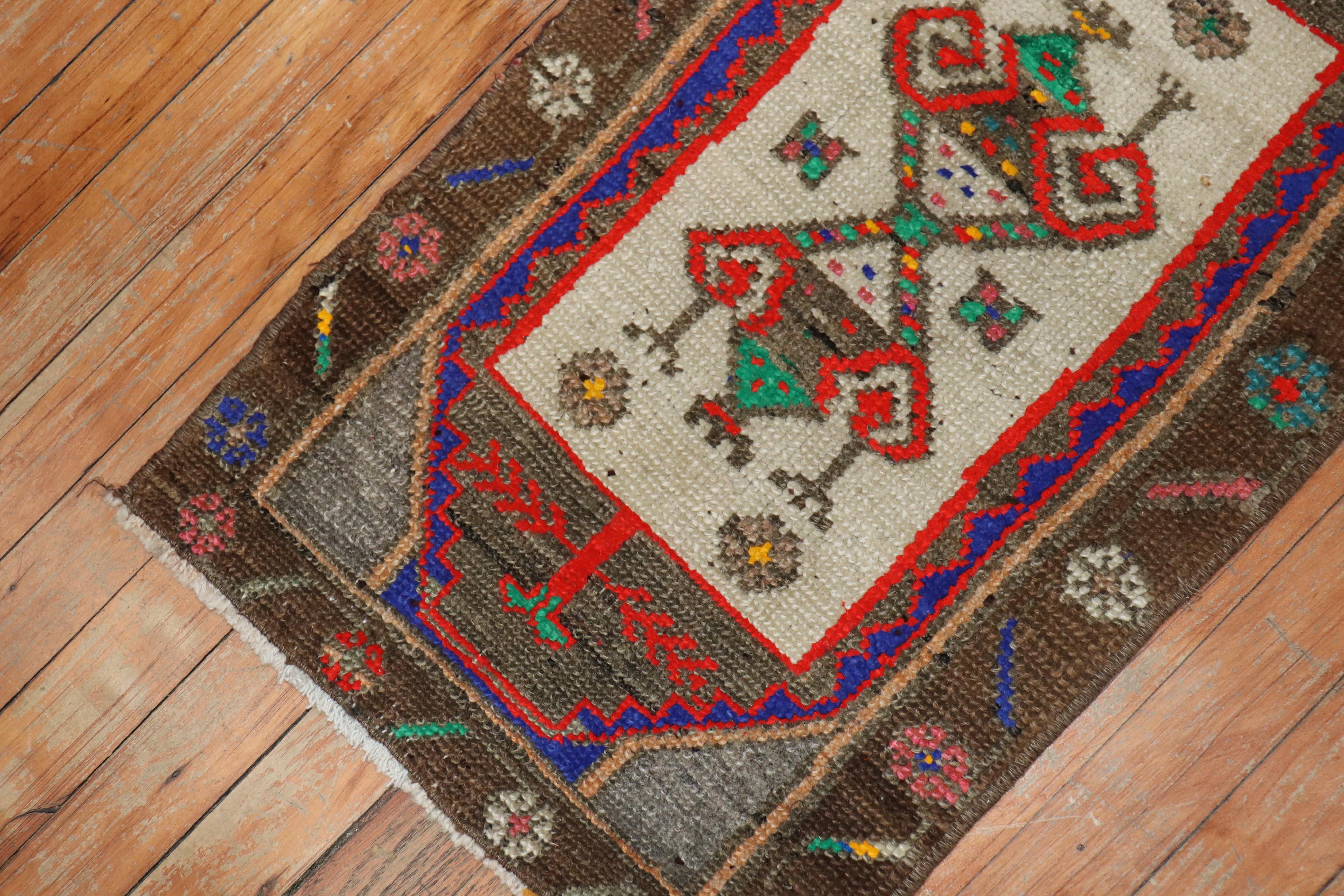 A vintage Anatolian Turkish Yastik rug mat with a chocolate brown border, cotton accents in green, pink, red, yellow and purple-blue

Measures: 1'5” x 2'7”.