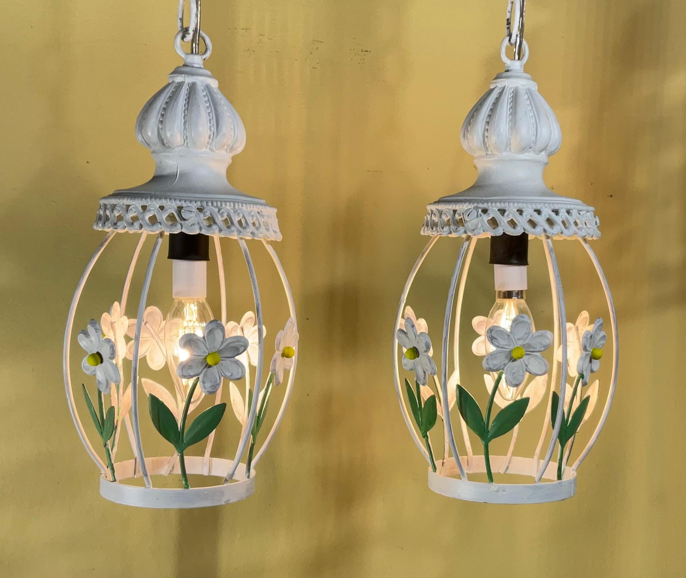 
Eleva il tuo spazio con questa affascinante coppia di lampade a sospensione vintage French Country. Ogni lampada presenta un'elegante struttura in metallo bianco ornata da delicati fiori di margherita dipinti a mano, per dare un tocco di estroso