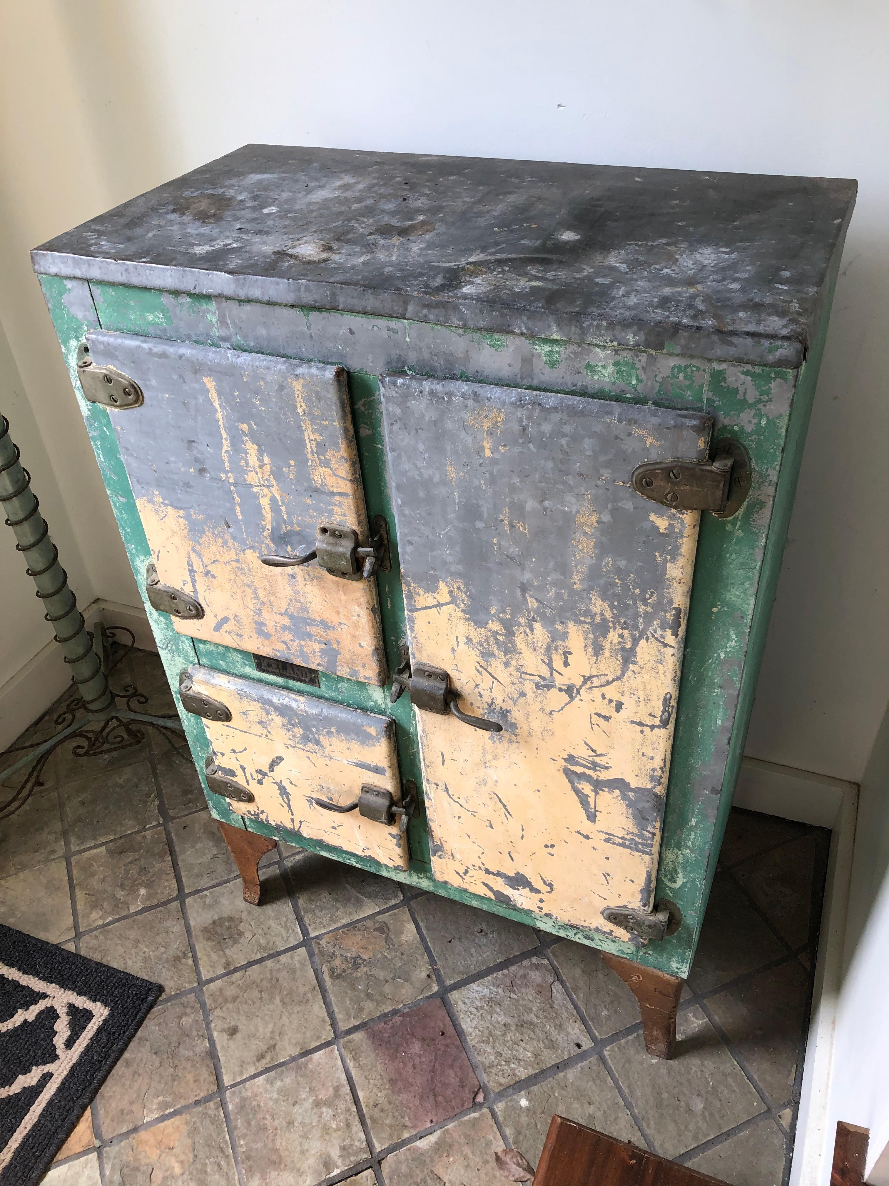 Wonderful vintage metal icebox with fabulous distressed green and cream paint with original silver showing through. Interior offers functional storage space, most recently used in an artist's studio.