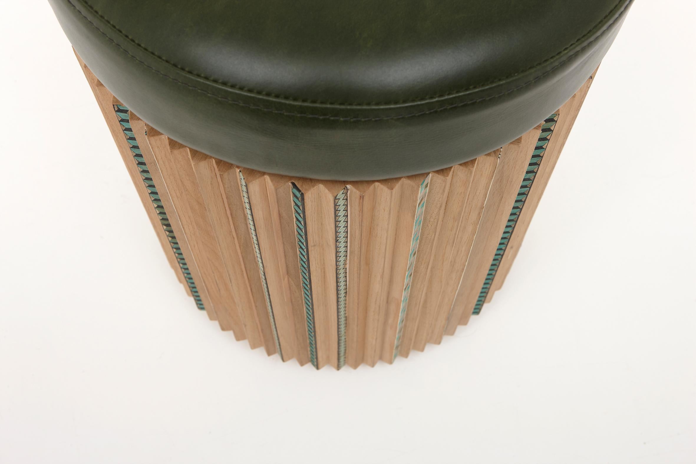 The stool in leather swivels above a pleated wood base.