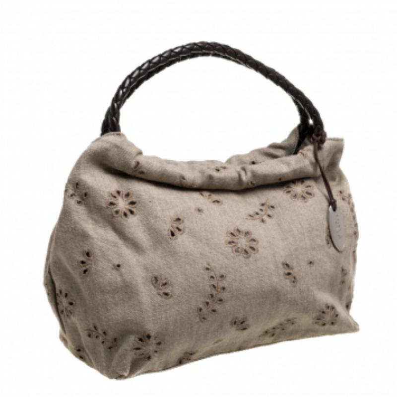 Furla's shoulder bag expresses the label's incredible craftsmanship and distinctive aesthetics. Made from canvas in a beige shade, the exterior is adorned with cutout floral motifs and a logo charm. The braided dual handles are made from leather to