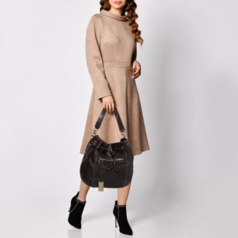 This hobo from Furla is crafted from leather in a dark brown hue. It has a zip pocket at the front, zip detailing on the contours a shoulder strap, and a drawstring closure that opens to a fabric-lined interior. Feminine in design, the bag is